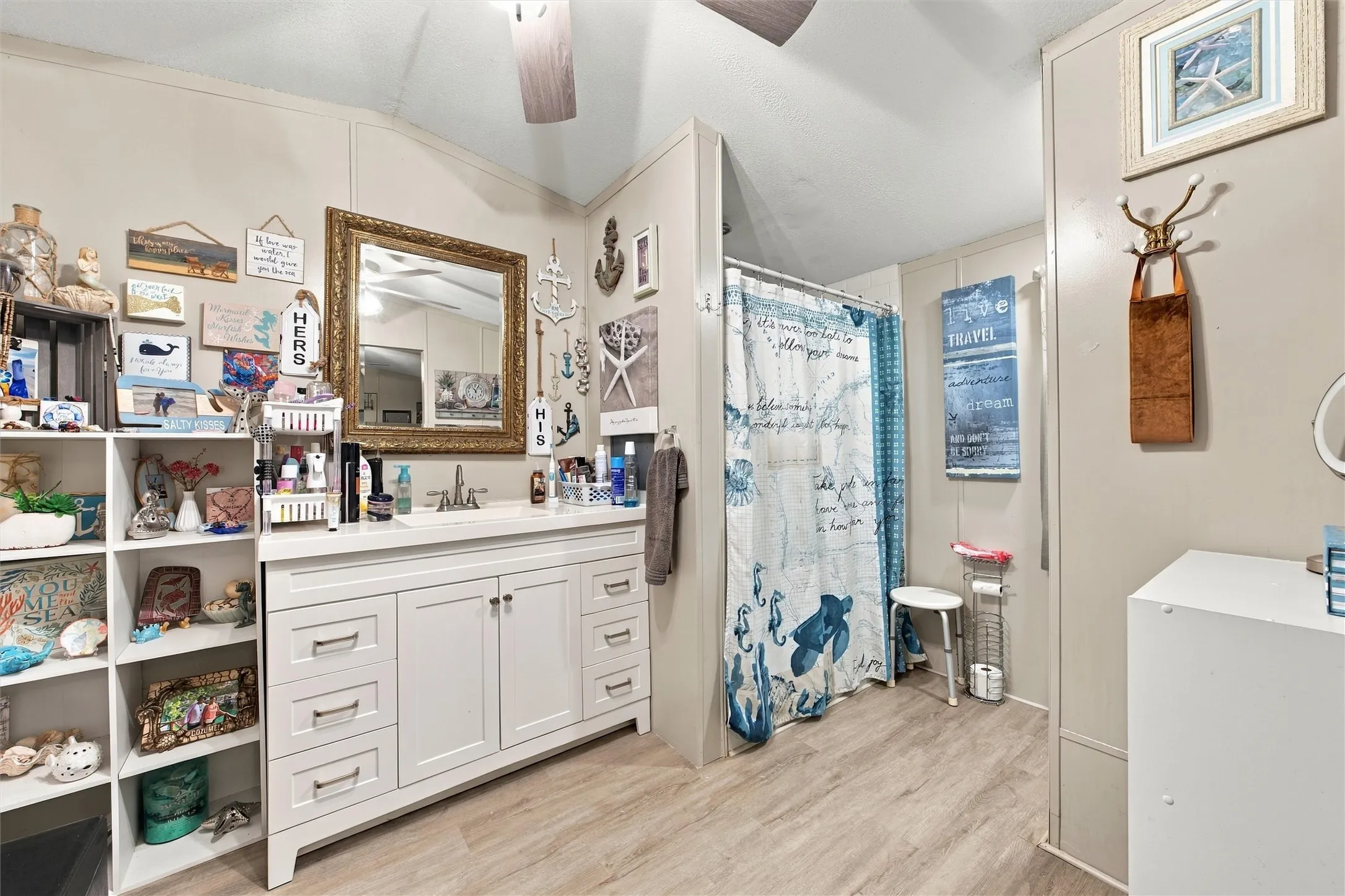 White vanity with multiple drawers and cabinet storage, single basin sink, and a framed mirror