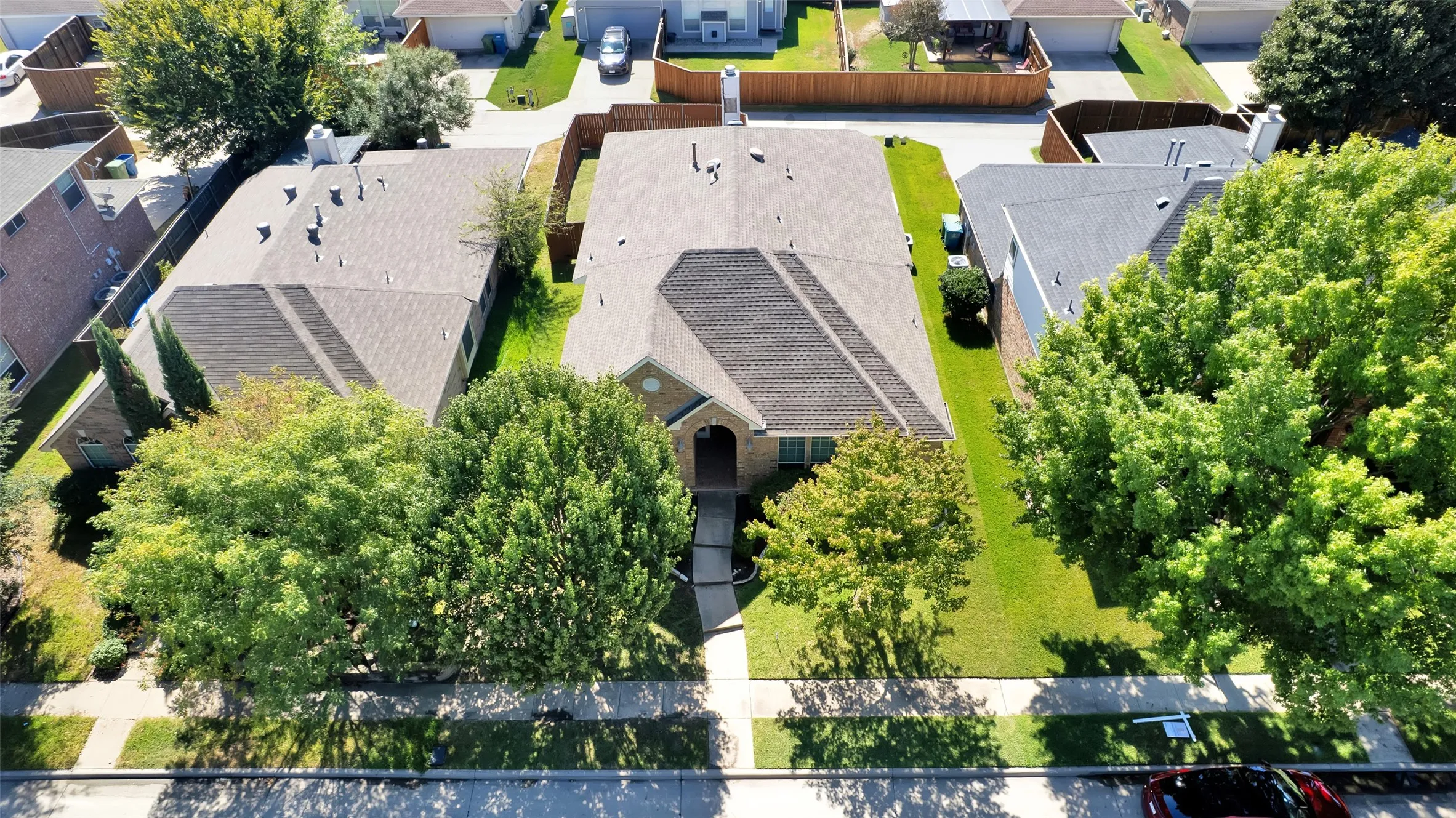 Gabled roofline, mature trees, concrete driveway, and a well-maintained lawn