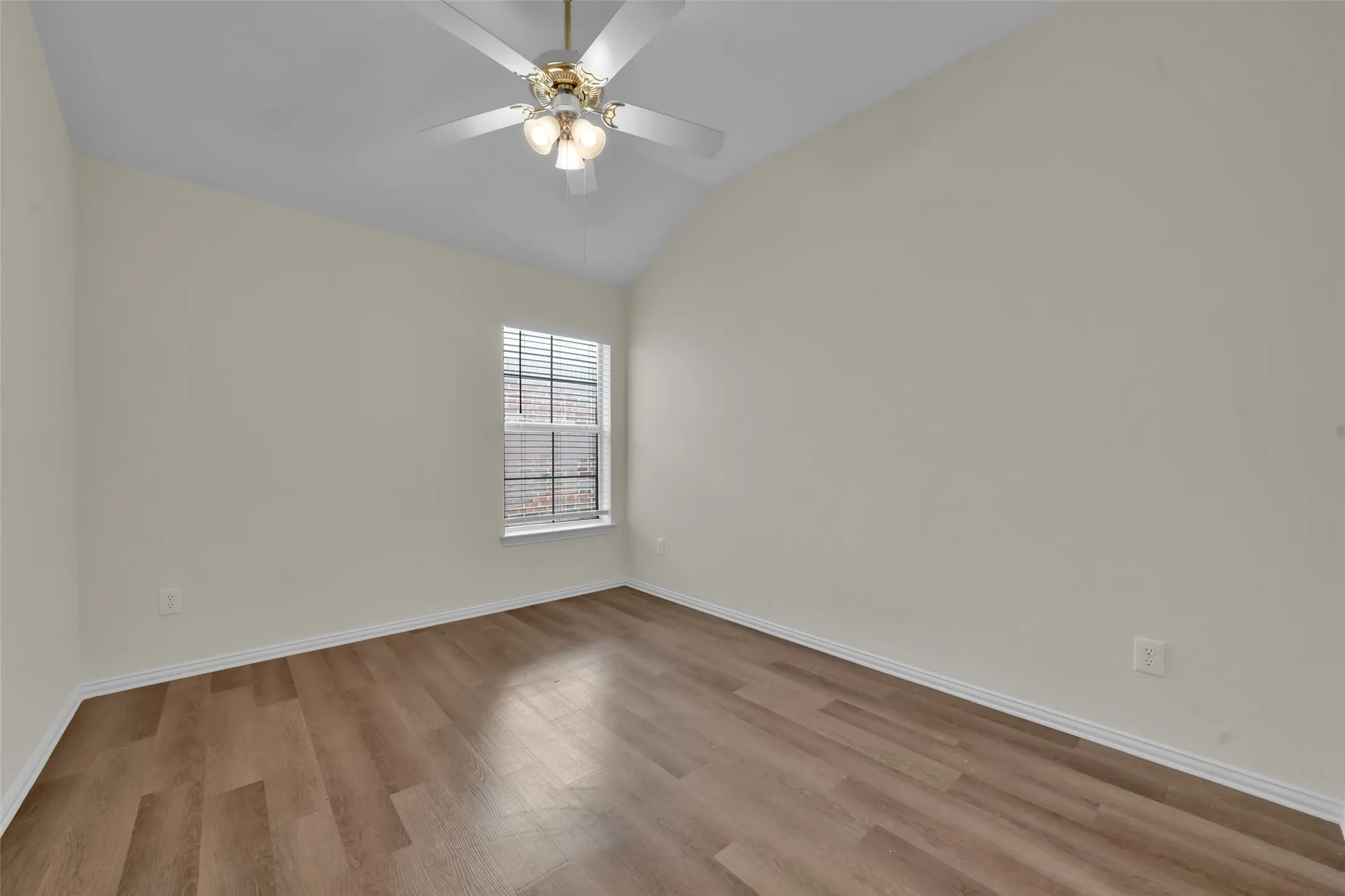 Vaulted ceiling with a ceiling fan, window with blinds, wood-finish flooring, and light-colored walls