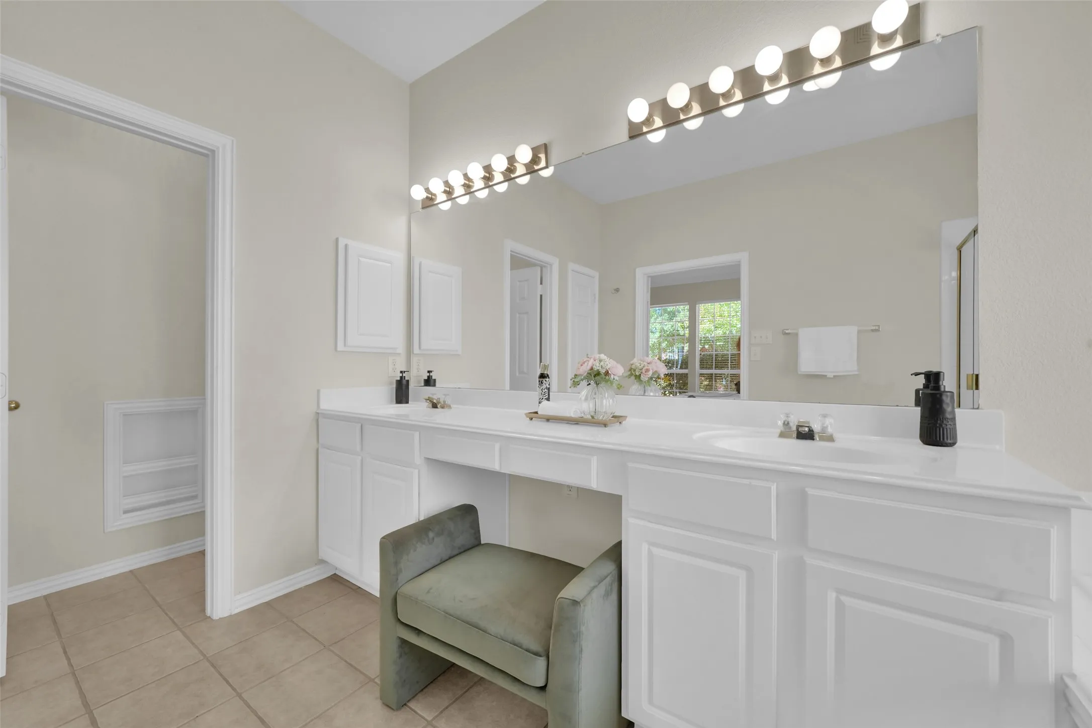 Dual vanity with white cabinetry, integrated sinks, white countertops, and a full-width mirror with overhead theatrical lighting