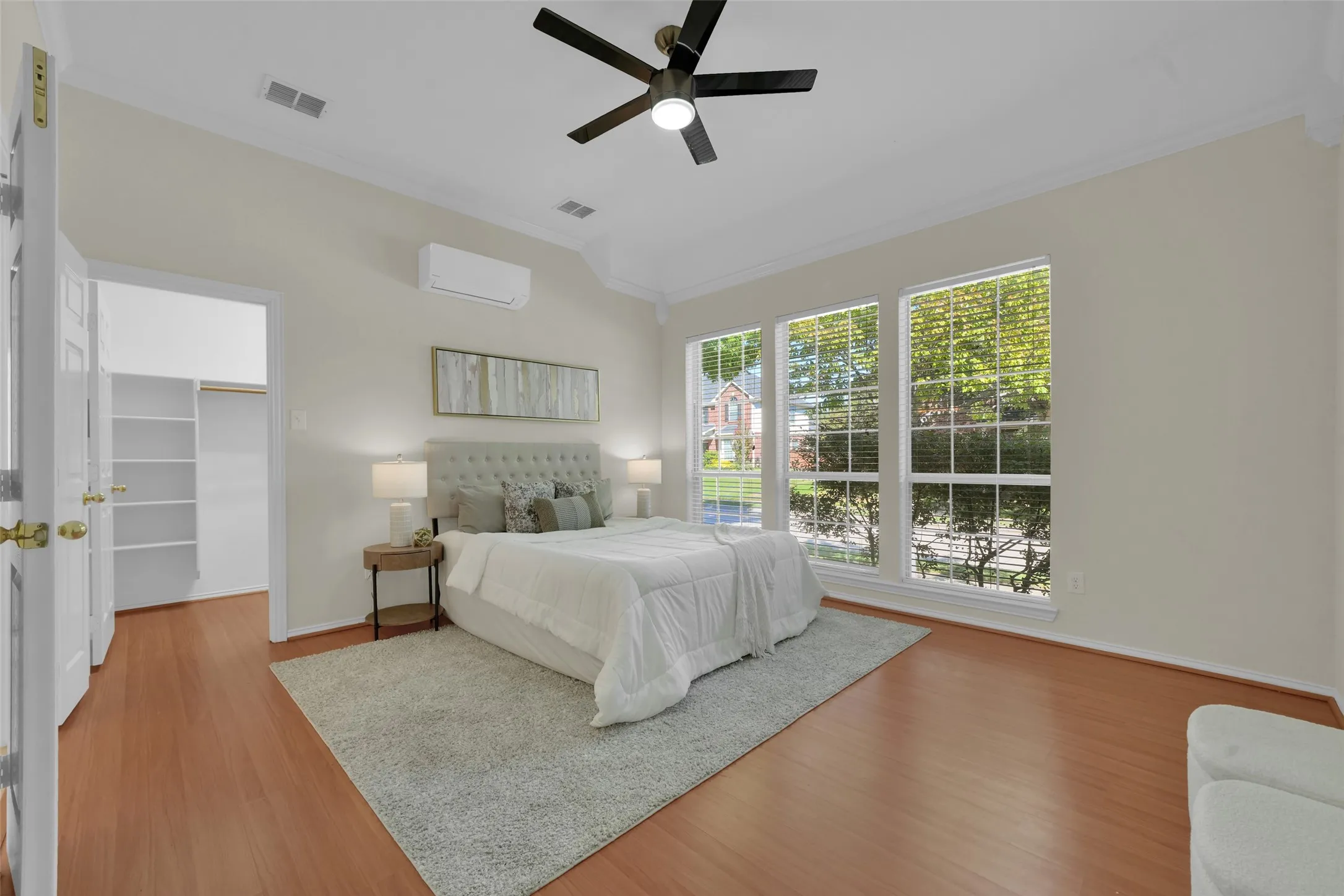 Wood-finish flooring with white baseboards, a ceiling fan, and three large windows