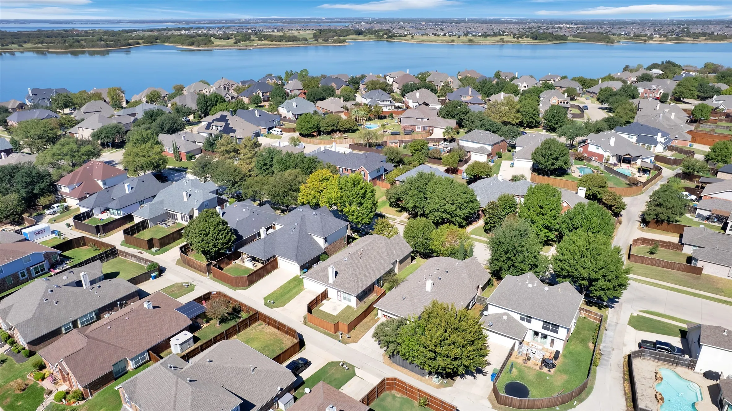 Residential community with mature trees and a substantial body of water in the background