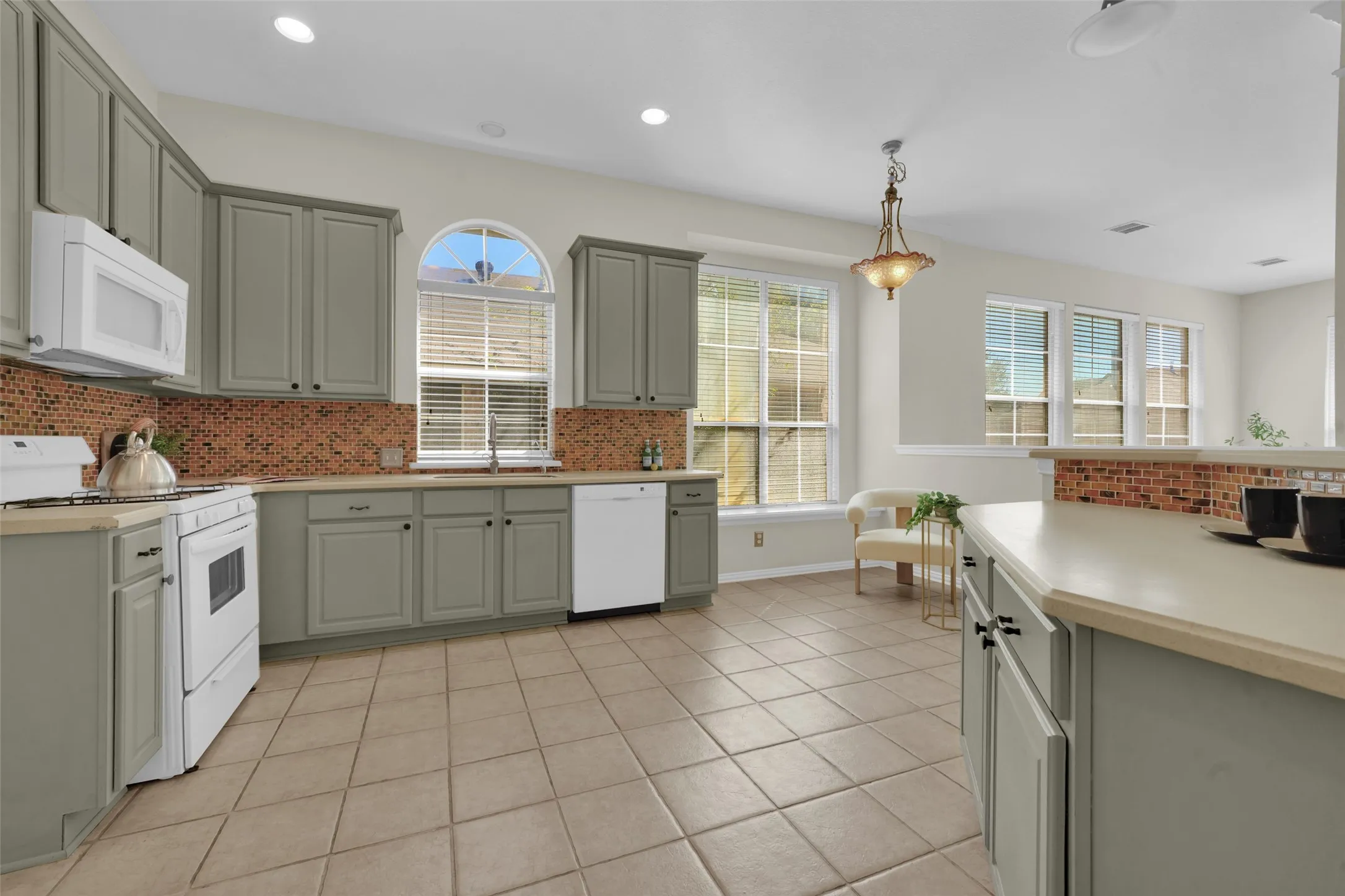 Kitchen featuring extensive cabinetry, tile backsplash, built-in appliances, recessed lighting, and a kitchen island with additional storage