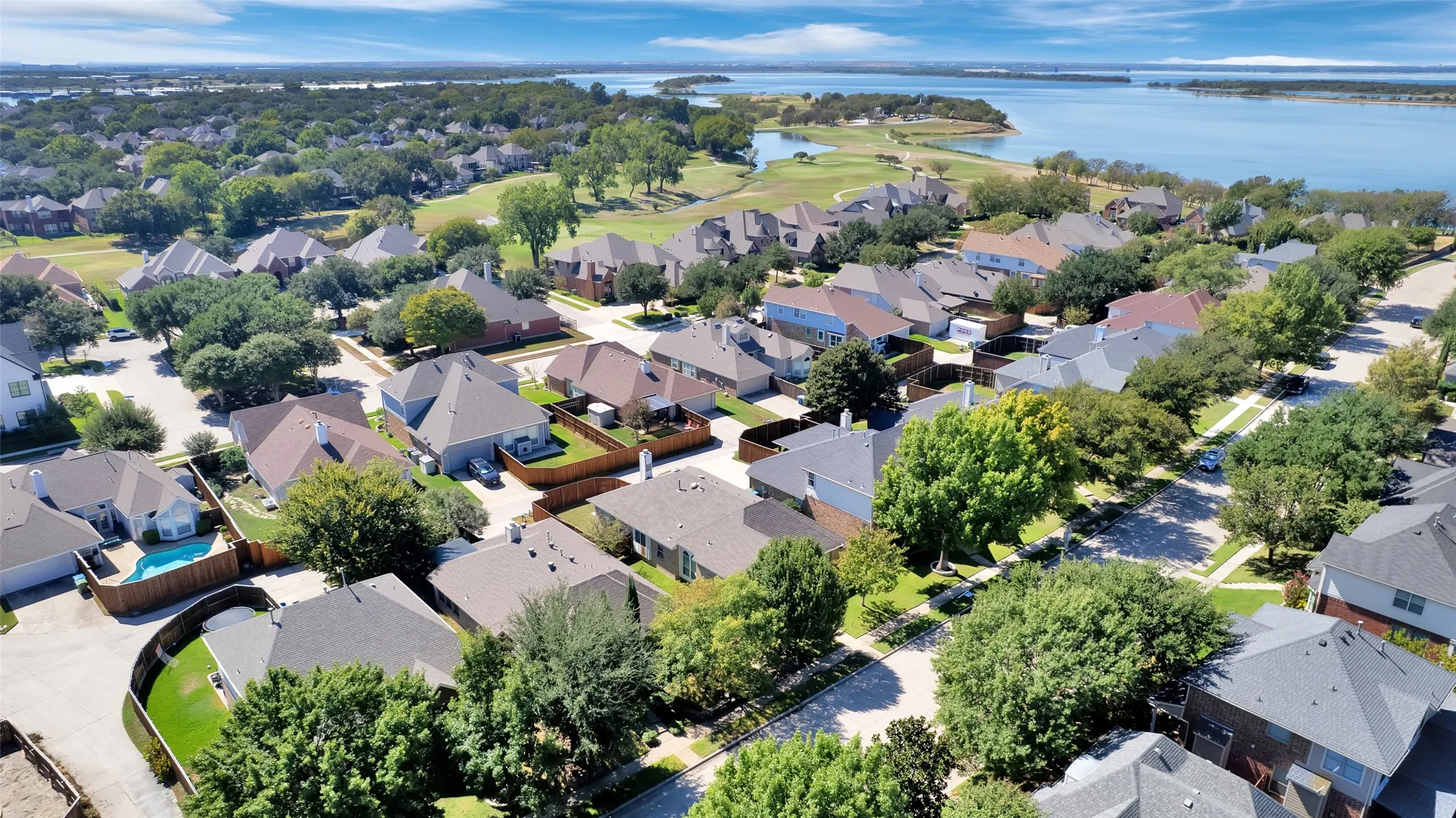 Lakeside community featuring a golf course, mature trees, and a variety of residential properties