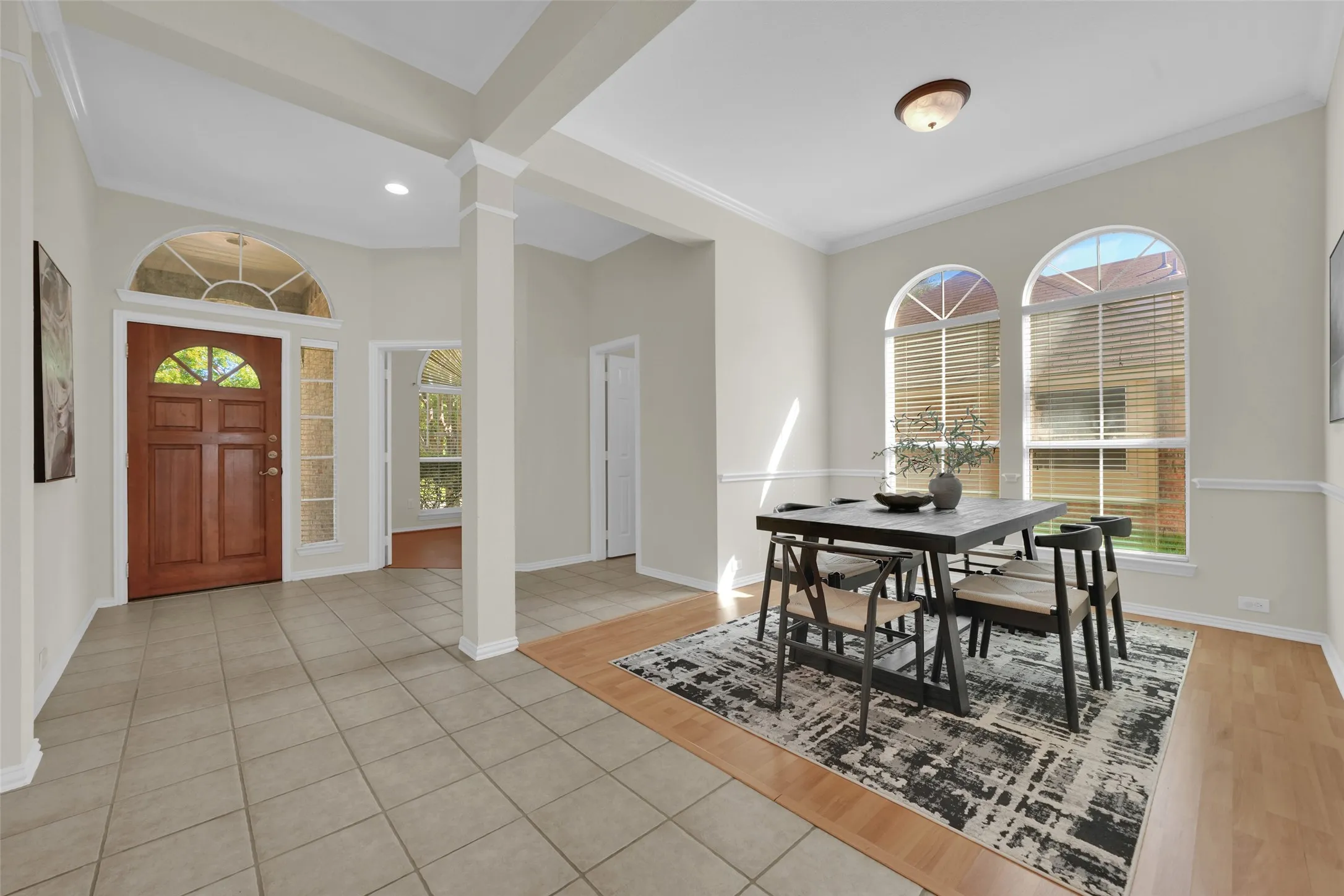 Entryway featuring a wood-panel door with an arched transom, tile flooring, and column detailing