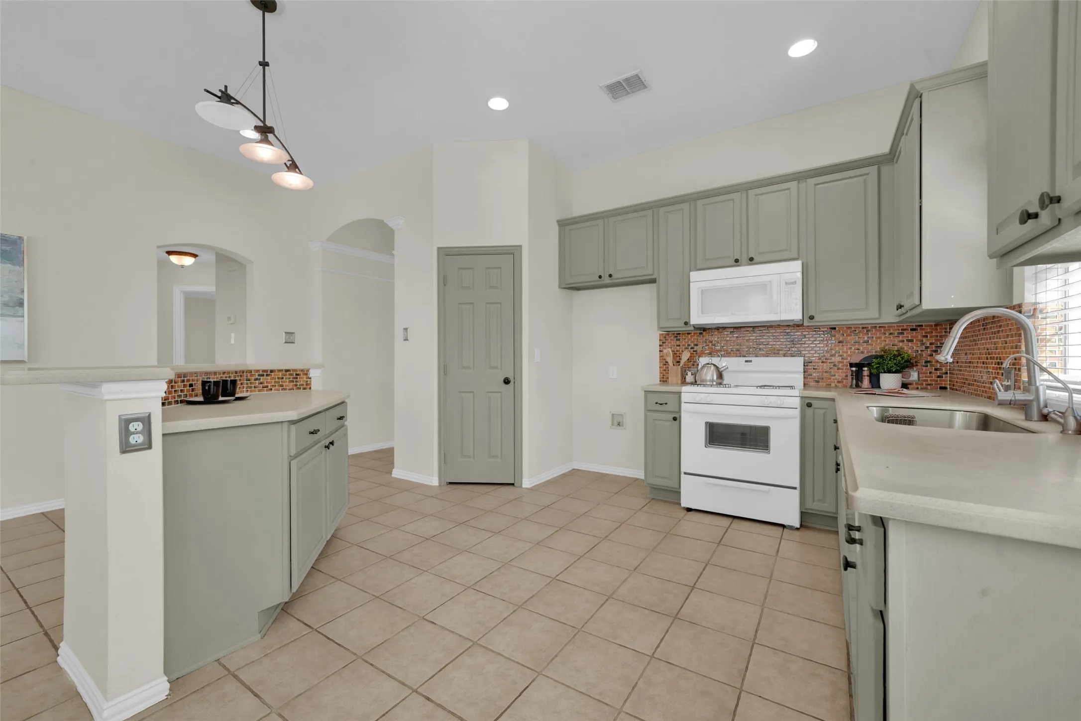 Kitchen featuring light-toned cabinetry, tile flooring, and a mosaic tile backsplash