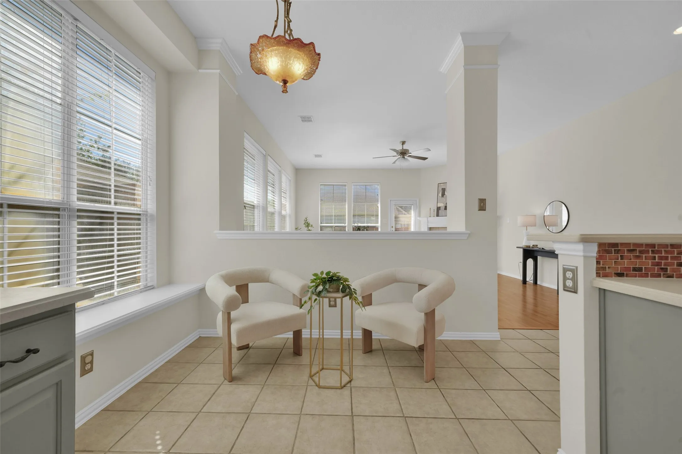 Tiled flooring with a warm finish, multiple windows with blinds, architectural half-wall with brick-finish detailing, and an ornate ceiling fixture