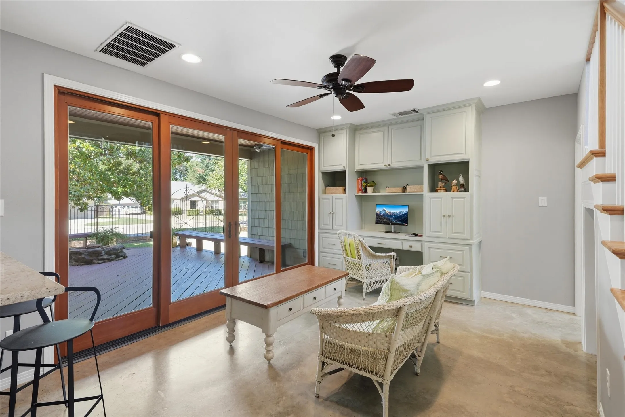 Versatile sunroom or flex space featuring polished concrete floors and custom built-in desk, plus a bar opening back into the kitchen