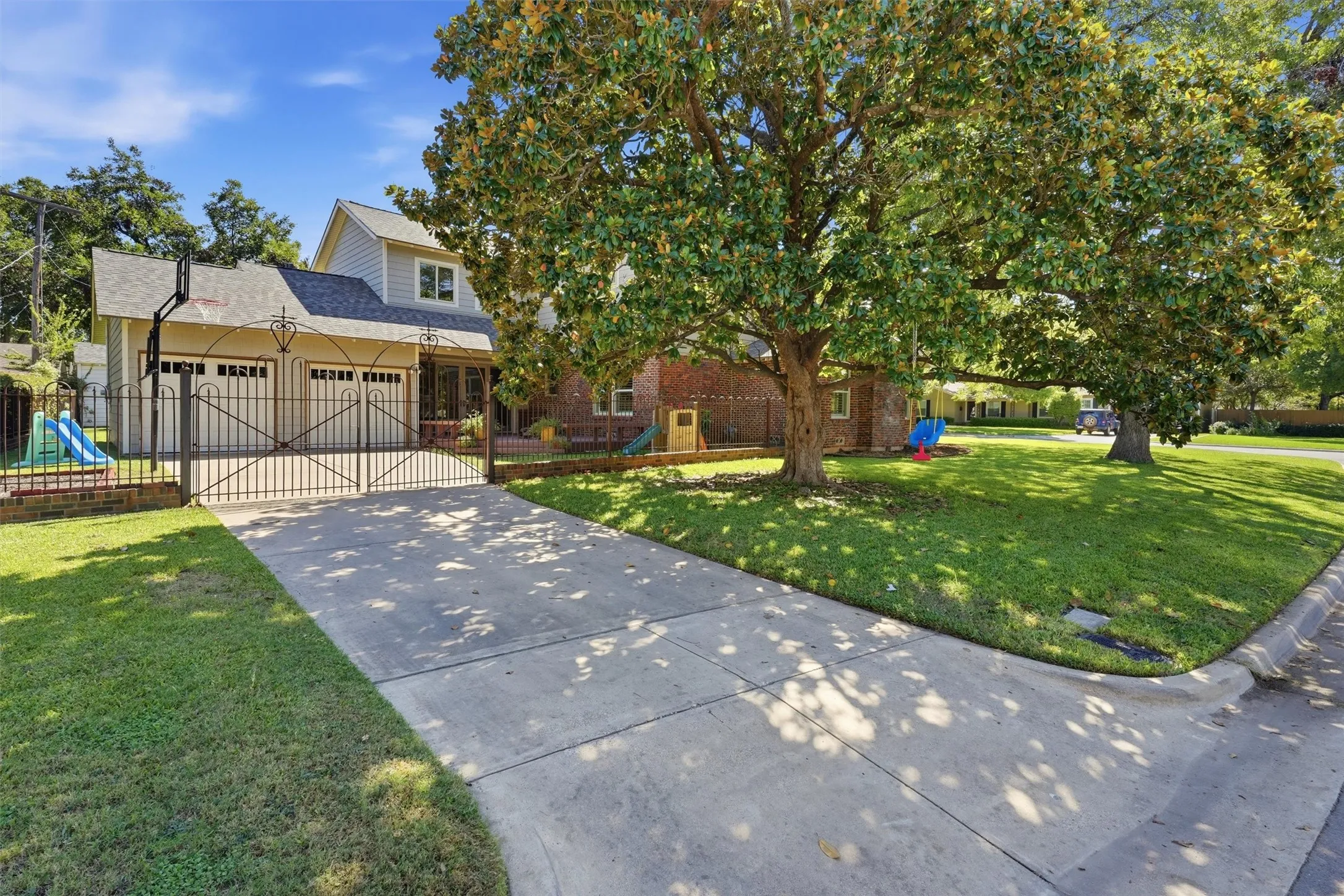 Wide view of the corner lot featuring mature trees providing large shade for evening family time.