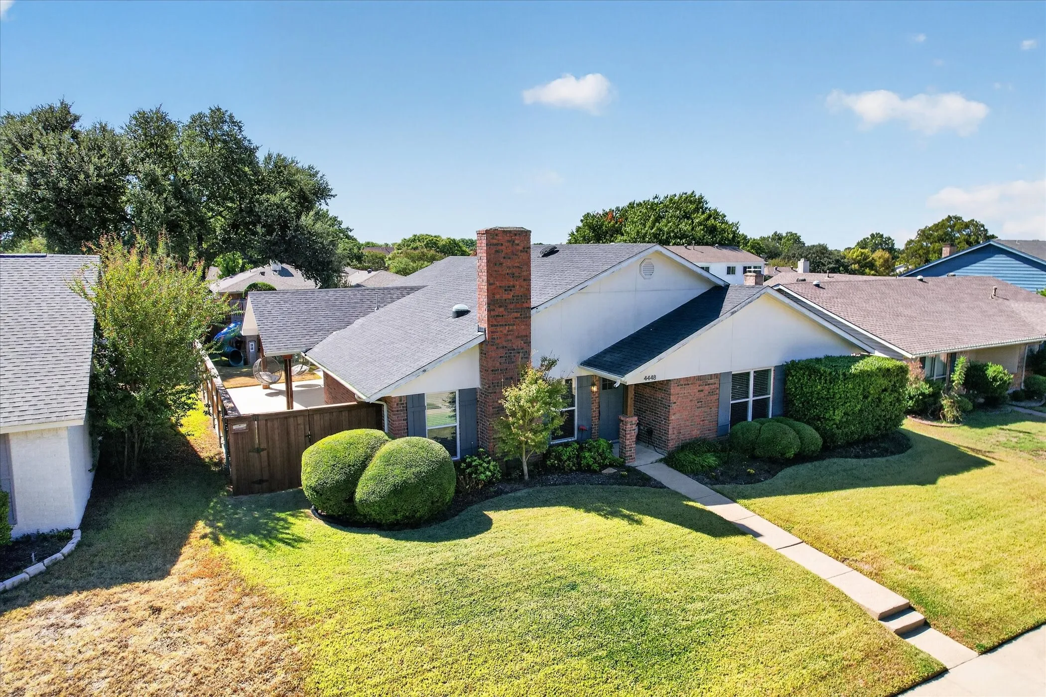 An elevated view showcases the home’s distinctive rooflines, prominent brick chimney and inviting outdoor spaces.