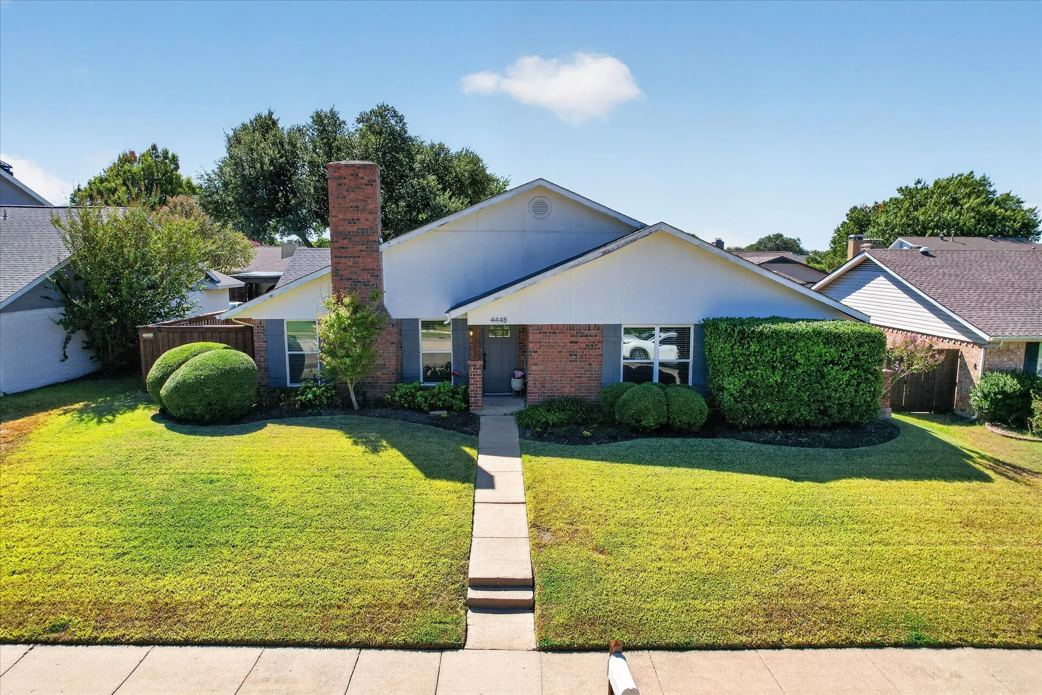 A welcoming front walkway, neatly shaped shrubs and a covered entry complement this home’s timeless brick exterior.