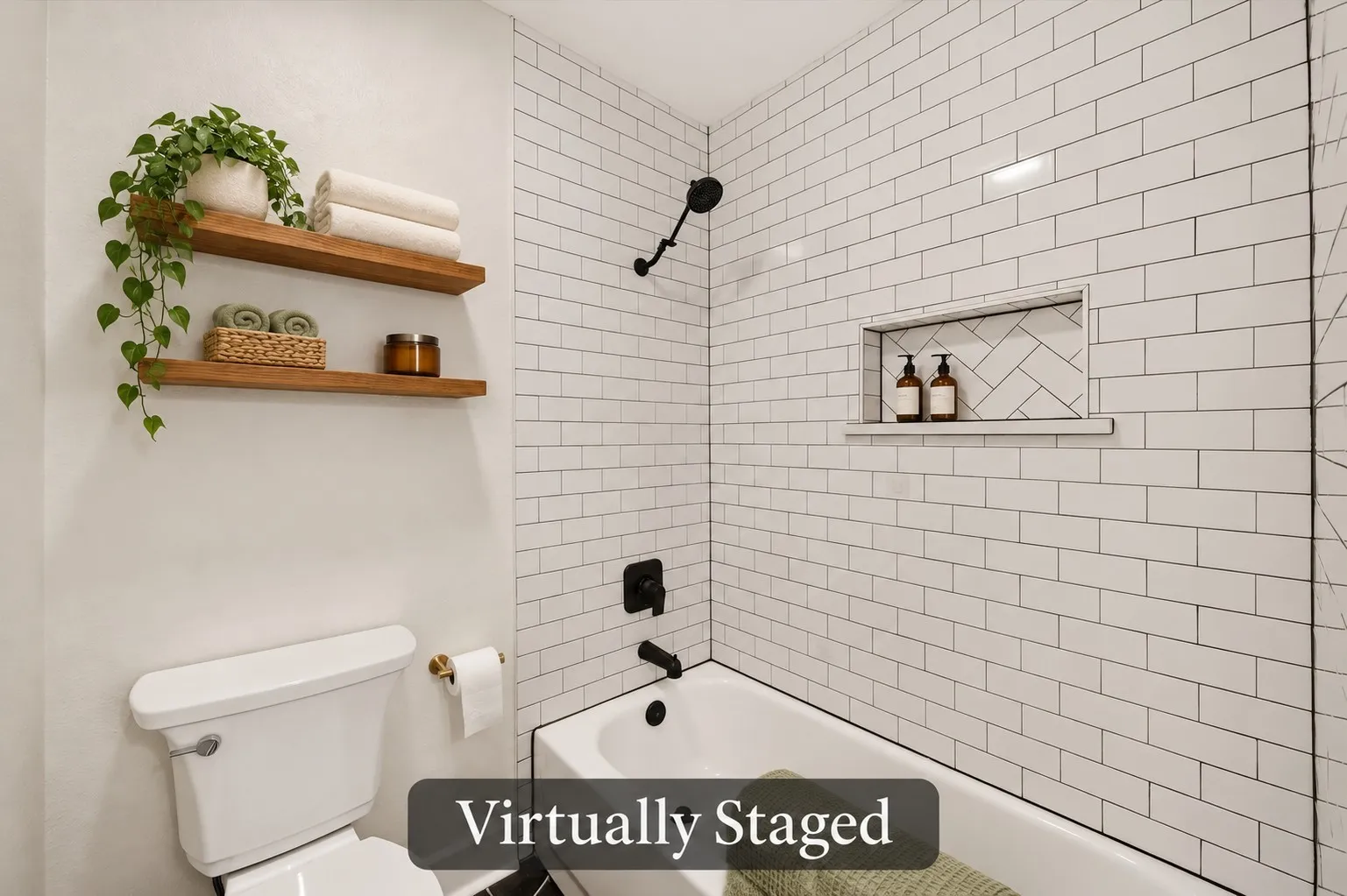 Classic white subway tile, contrasting black fixtures and a recessed shampoo niche give the hall bath’s tub-shower combination a polished look. Virtually staged.