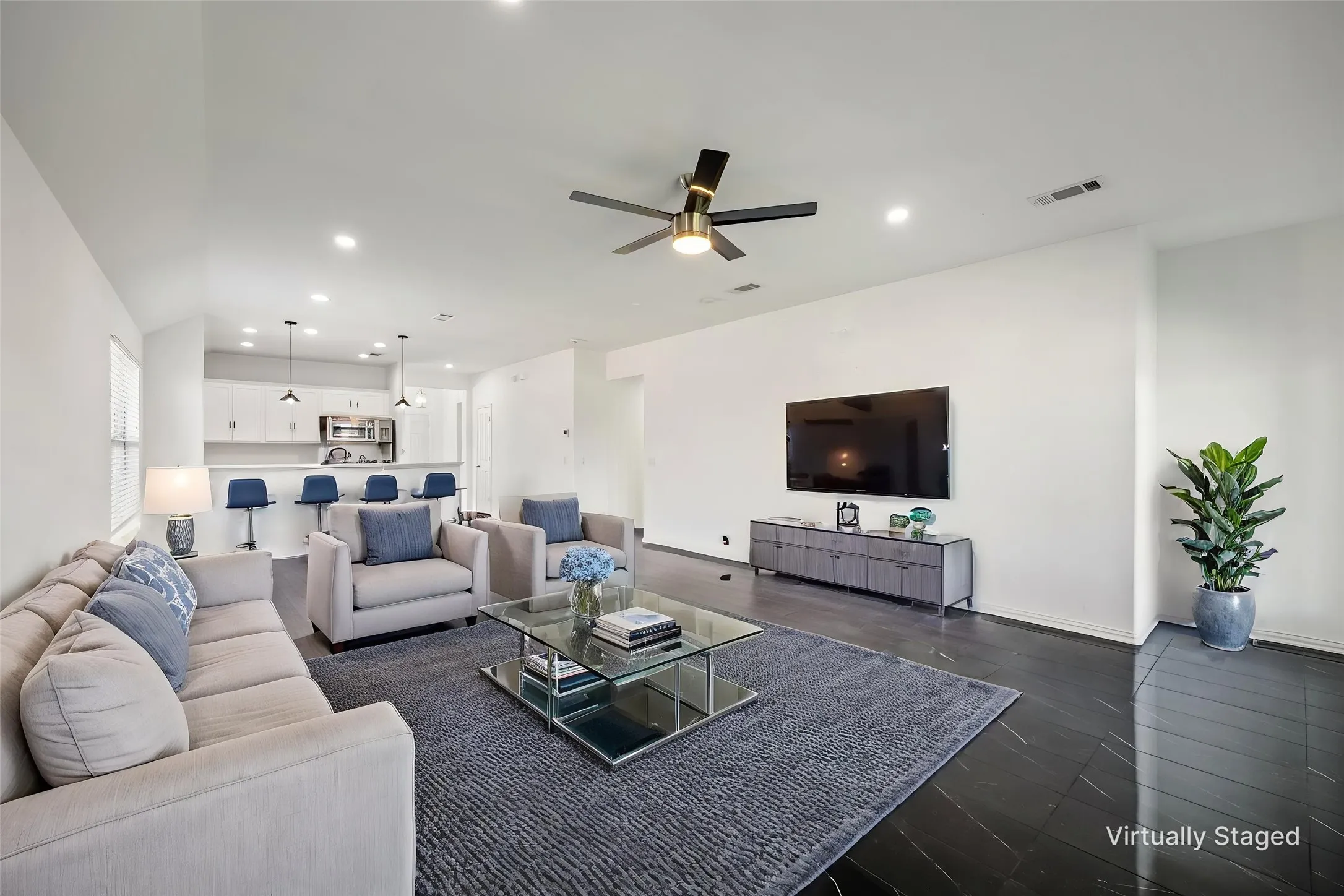 Open-concept living space featuring high ceilings, dark wood-finish flooring, recessed lighting, and a contemporary ceiling fan