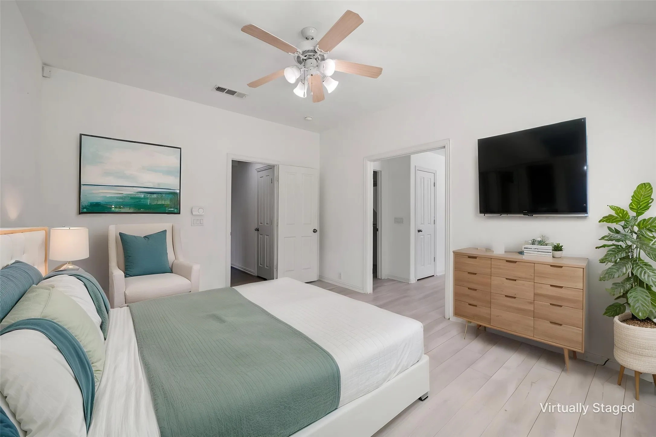 Light wood-finish flooring, ceiling fan with integrated lighting, and white interior doors
