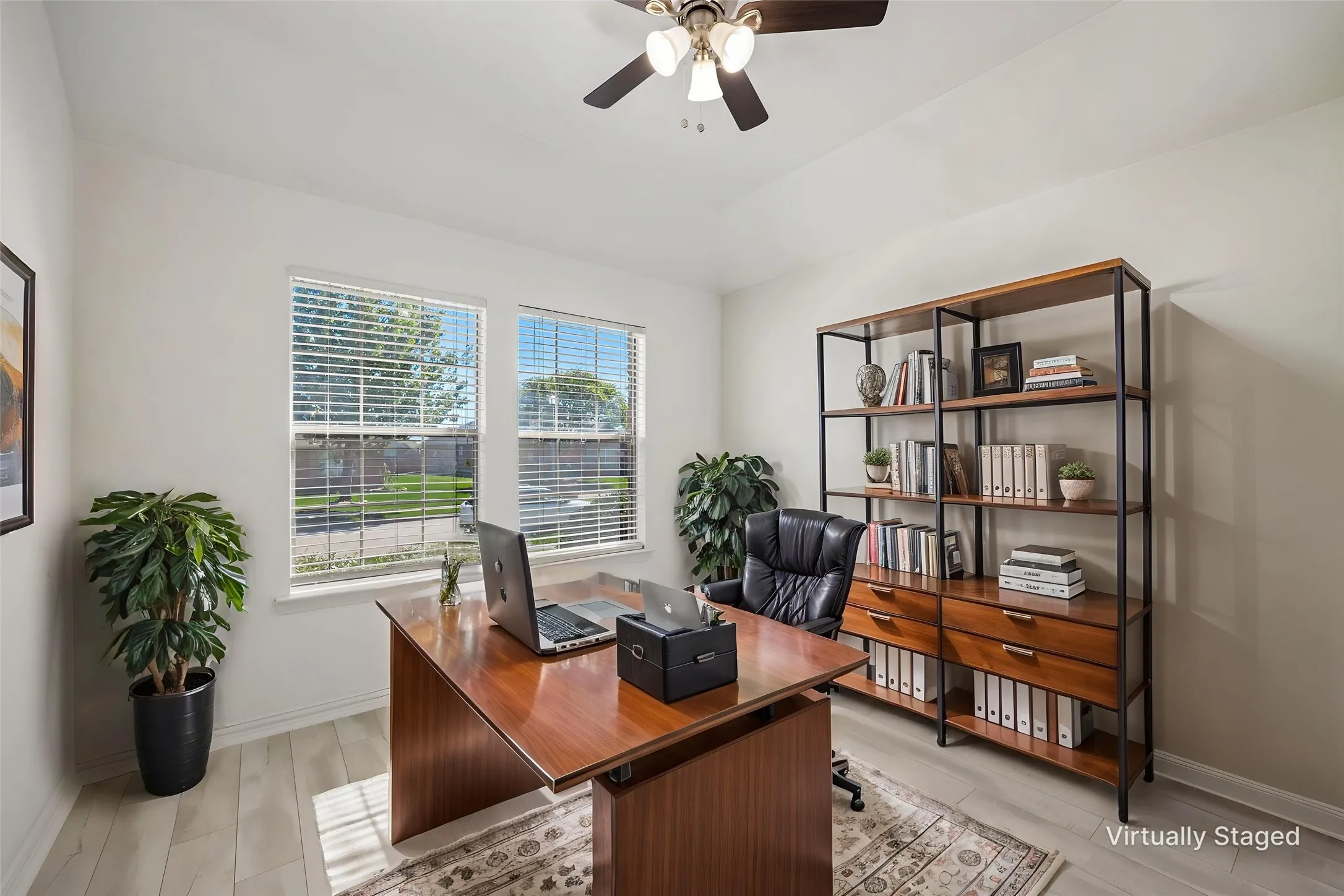 Light wood-finish flooring, two large windows with blinds, and a ceiling fan with integrated lighting