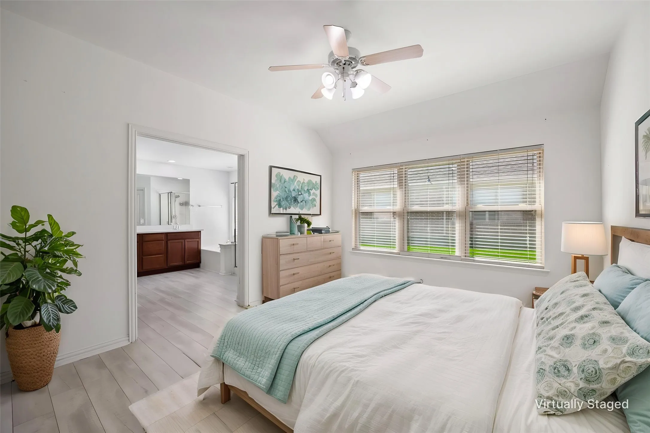 Vaulted ceiling with a ceiling fan, three-panel window with blinds, and light-tone wood-finish flooring
