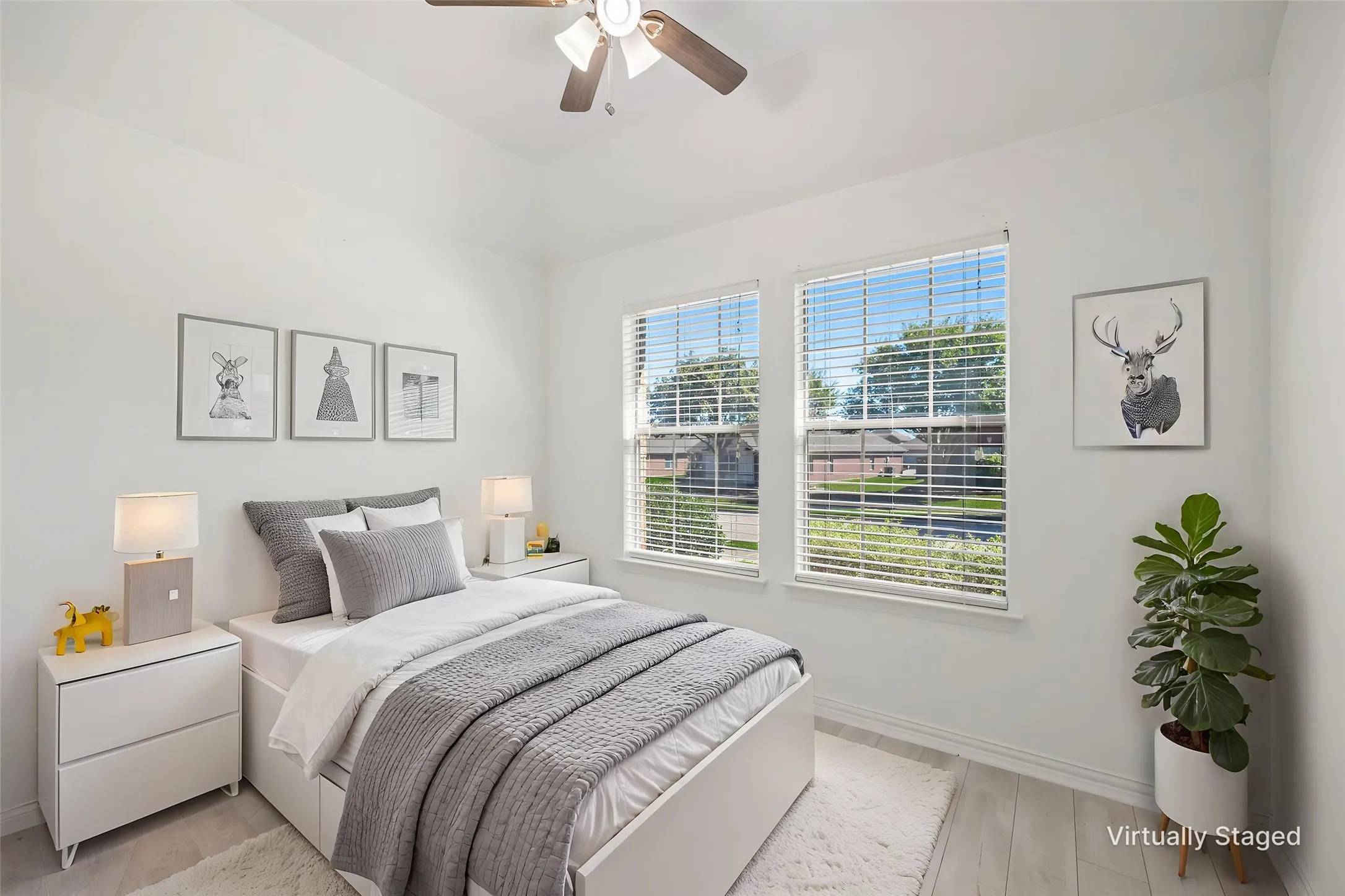 Vaulted ceiling with a ceiling fan, two windows, and light wood-finish flooring