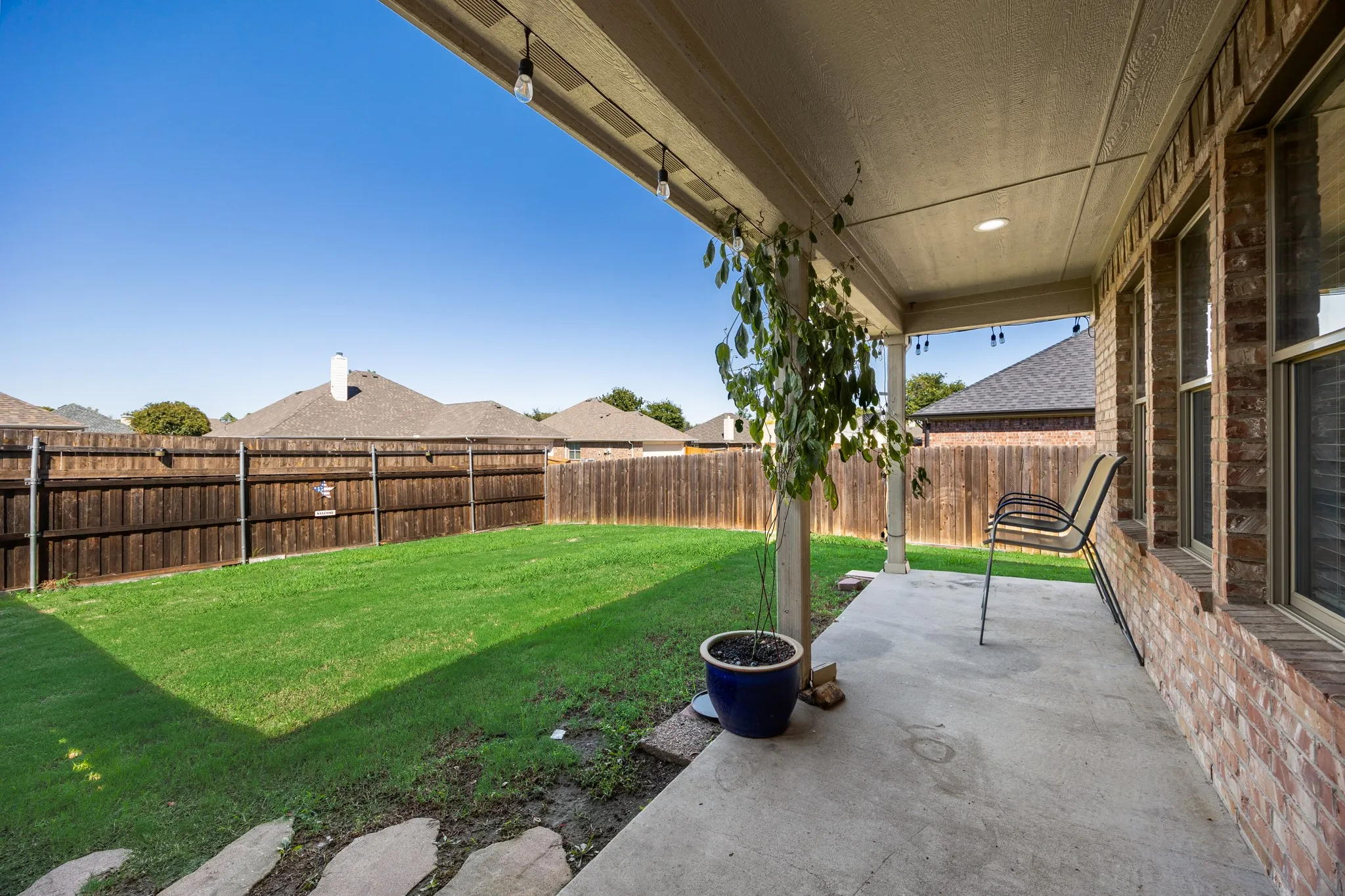Expansive concrete patio with recessed lighting and string lights, providing outdoor living space