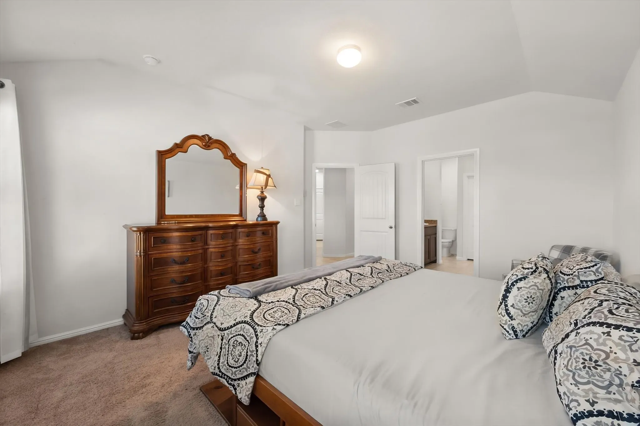 Carpeted bedroom featuring vaulted ceilings and a flush-mounted light fixture