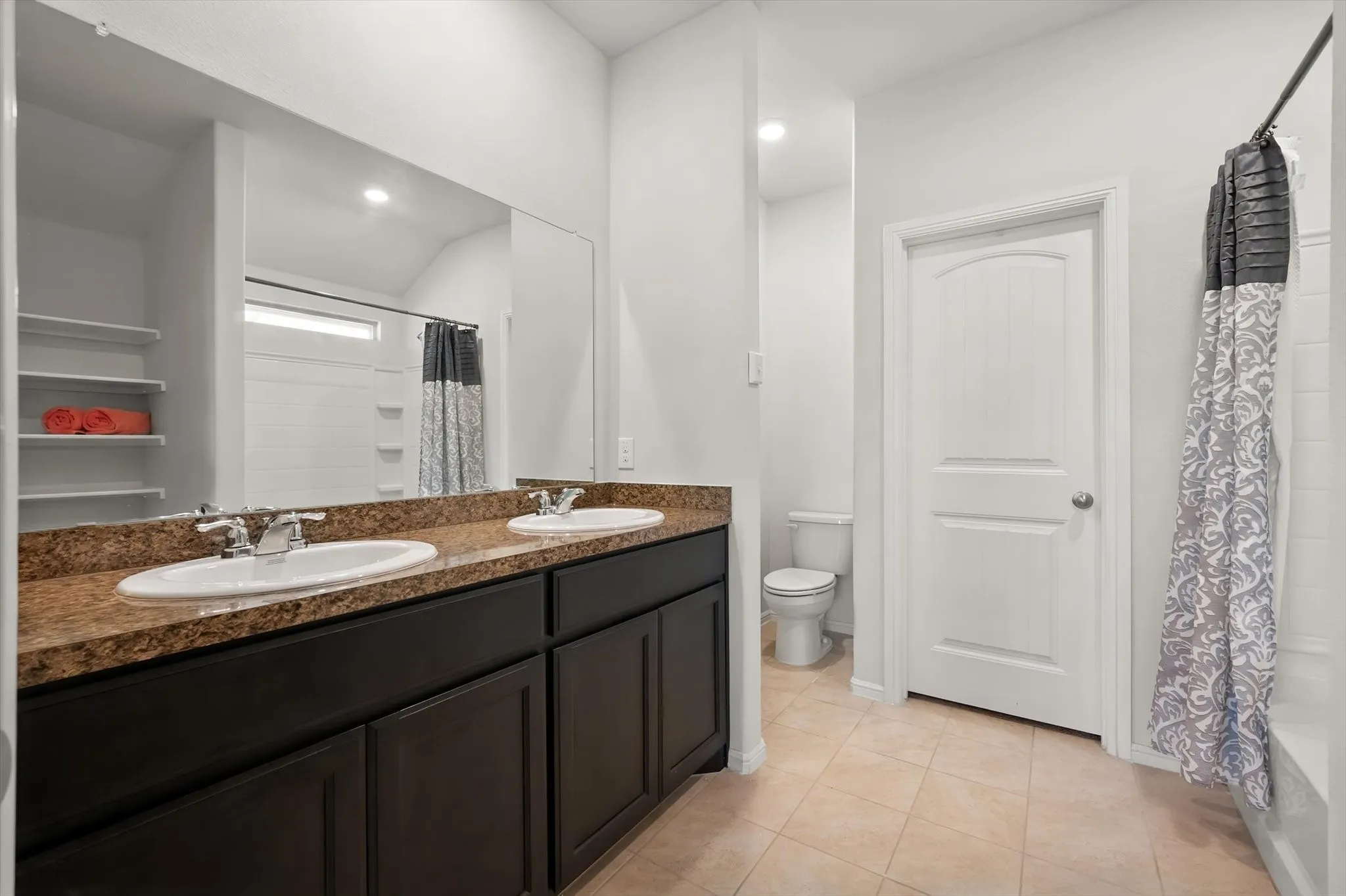 Dual vanity with brown-finish cabinetry and a stone-look countertop, featuring integrated sinks and polished chrome fixtures