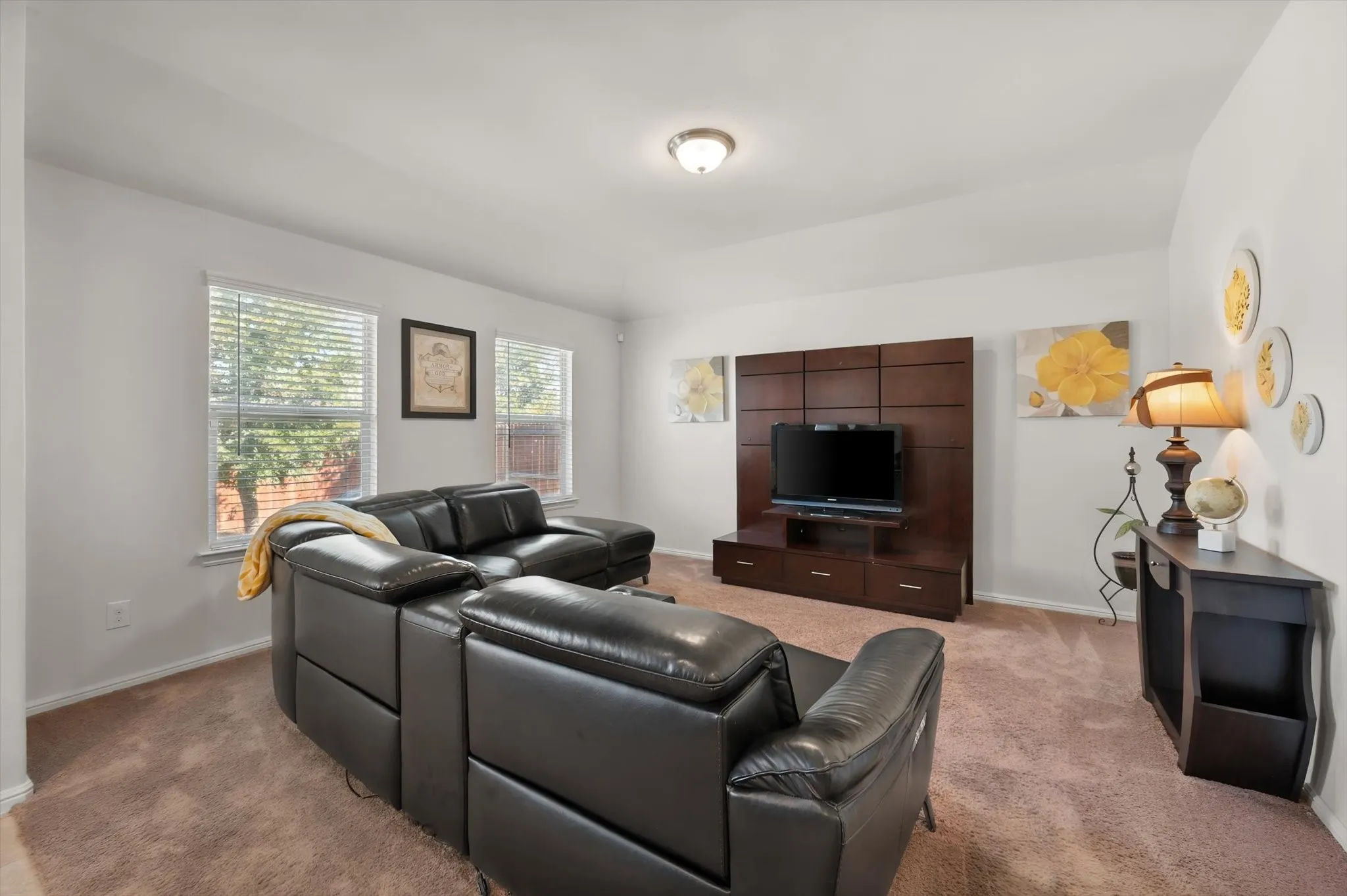 Wall-mounted media console with integrated storage, two large windows, recessed ceiling light fixture, and carpeted flooring