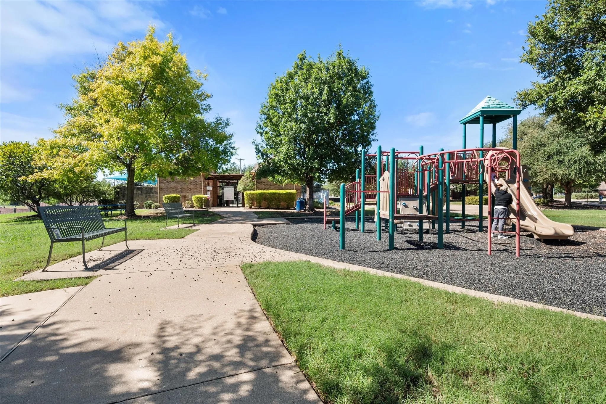 Playground featuring a slide, climbing wall, and monkey bars over a rubberized surface