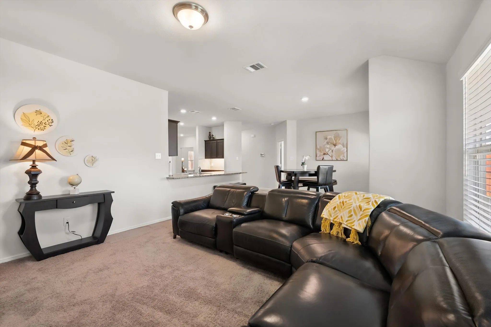 Open concept living area with broadloom carpeting, a contemporary flush mount ceiling light, and white window blinds