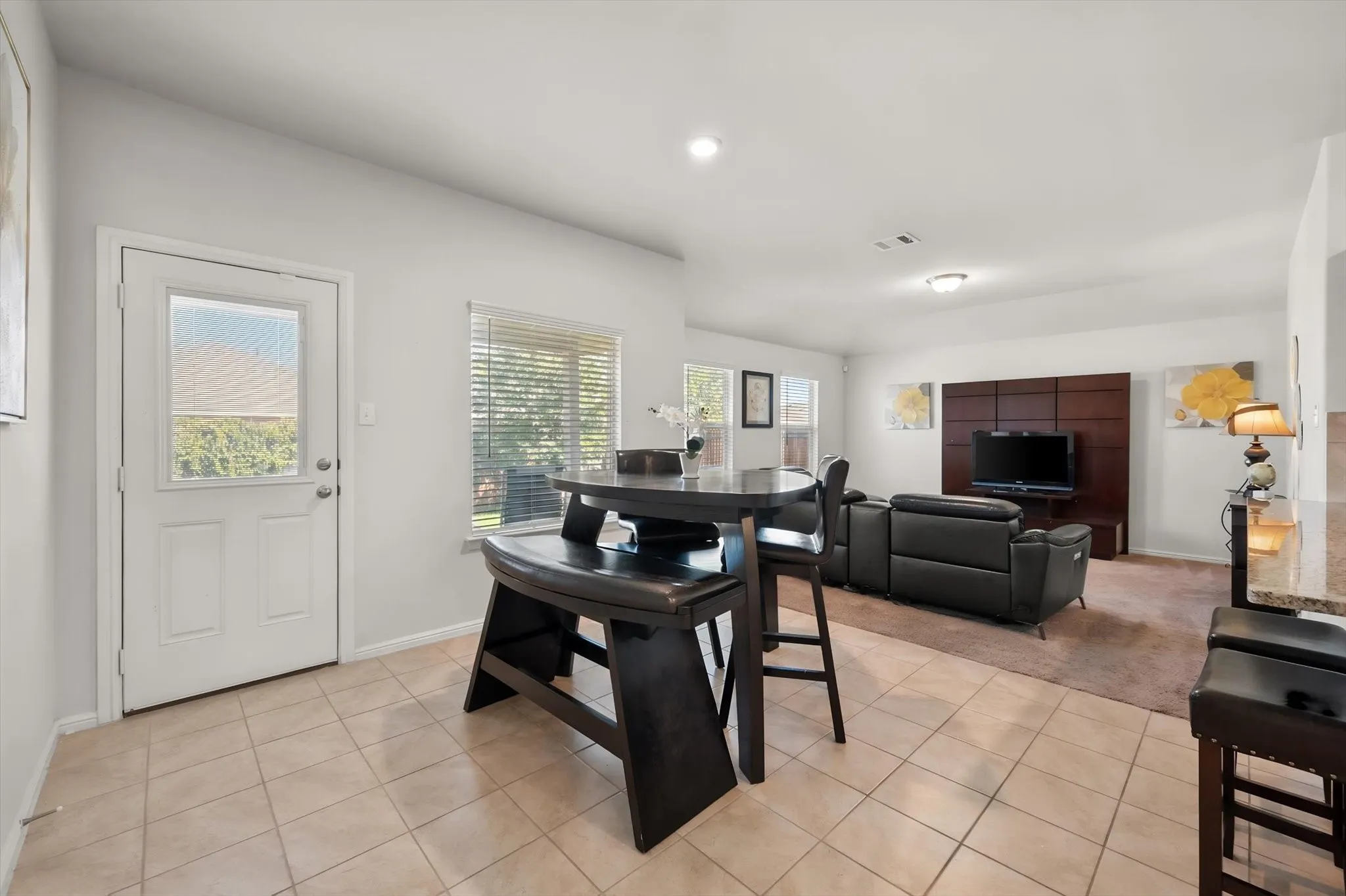 Tiled flooring, white paneled door with window, multiple windows with blinds, built-in entertainment center, and recessed lighting