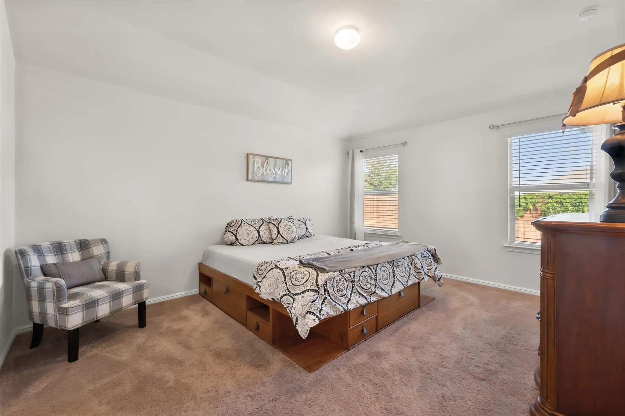 Carpeted flooring, two windows with horizontal blinds, and a flush mount ceiling light