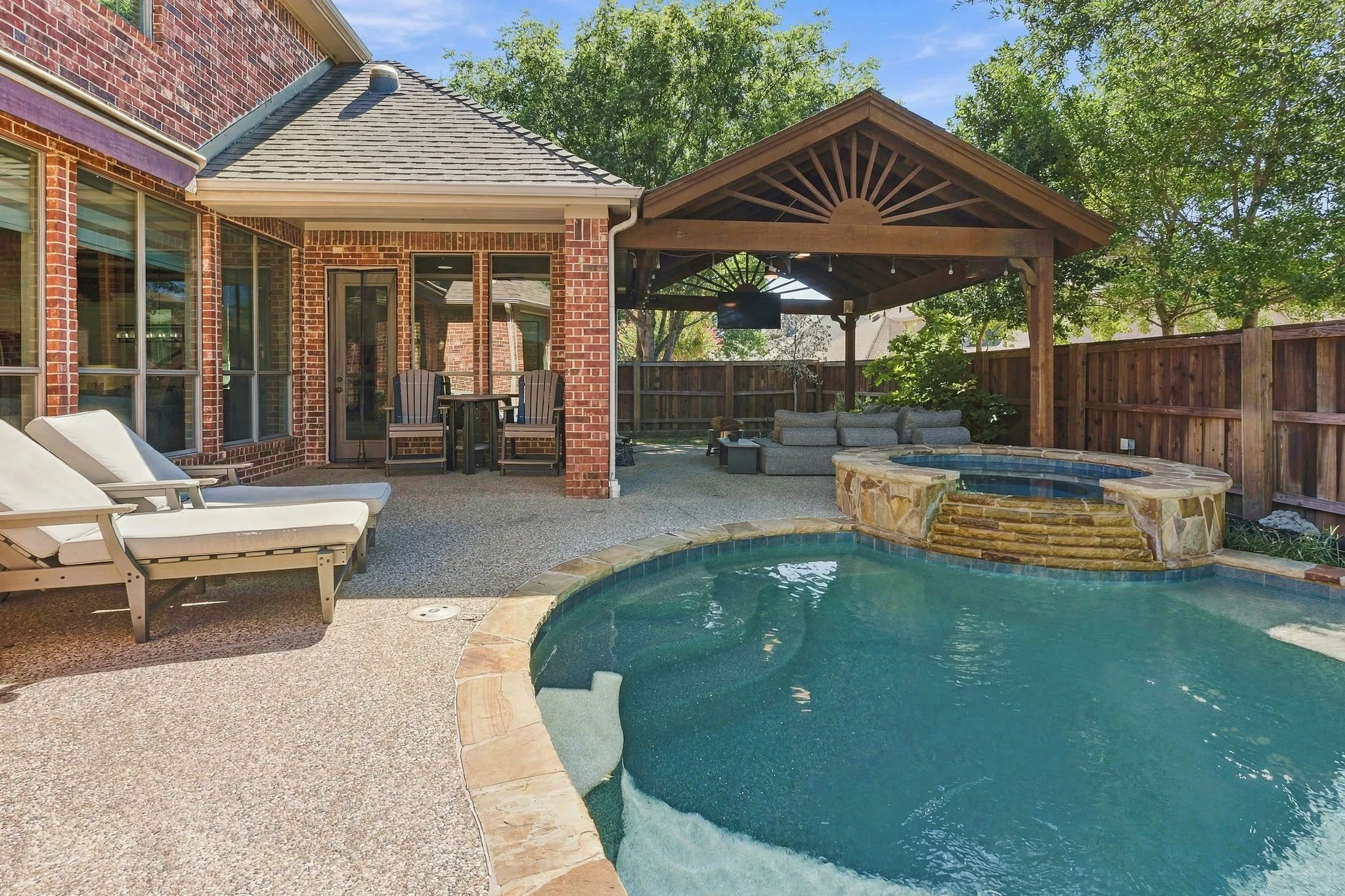 Pool, Spa and Covered Patio | Curved pool edges and the raised spa complement the adjacent covered outdoor living space.