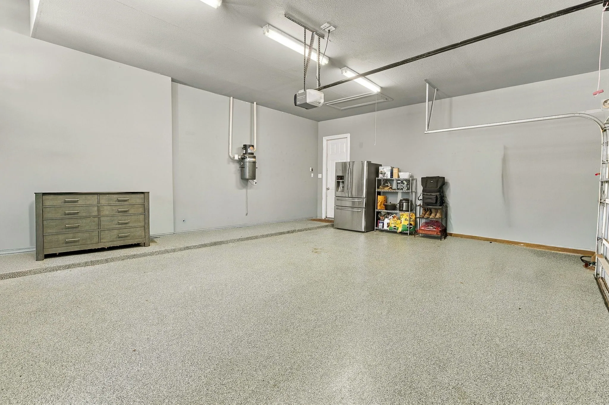 Three-Car Garage | Spacious garage with epoxy-finished floors, overhead lighting and room for vehicles and storage.