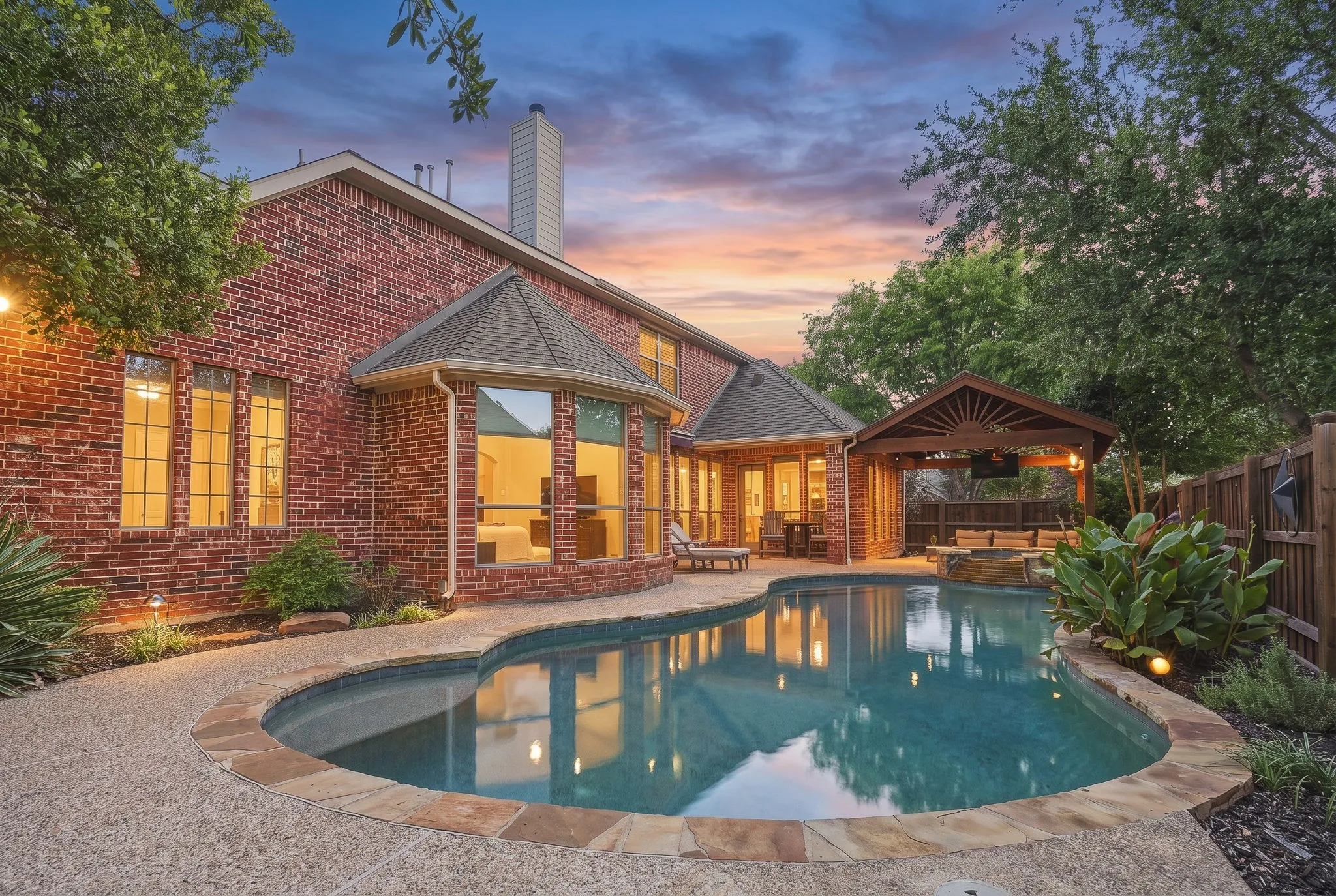 Backyard Pool at Twilight | Evening view of the private pool, rear elevation and covered outdoor living area at this Stonebridge Ranch home.