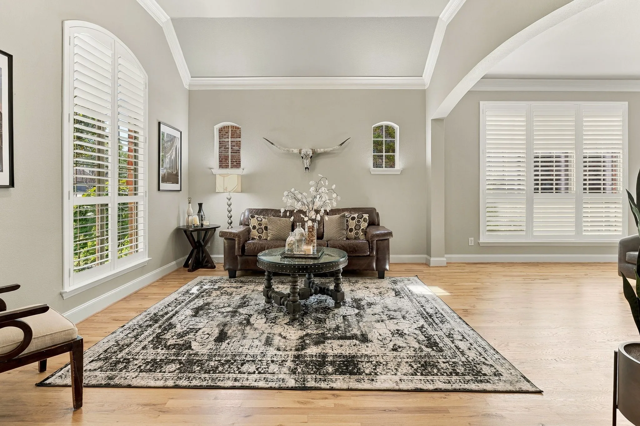 Formal Living Room | Front living space with wood flooring, tall windows, crown molding and an arched opening to the adjacent formal dining area.