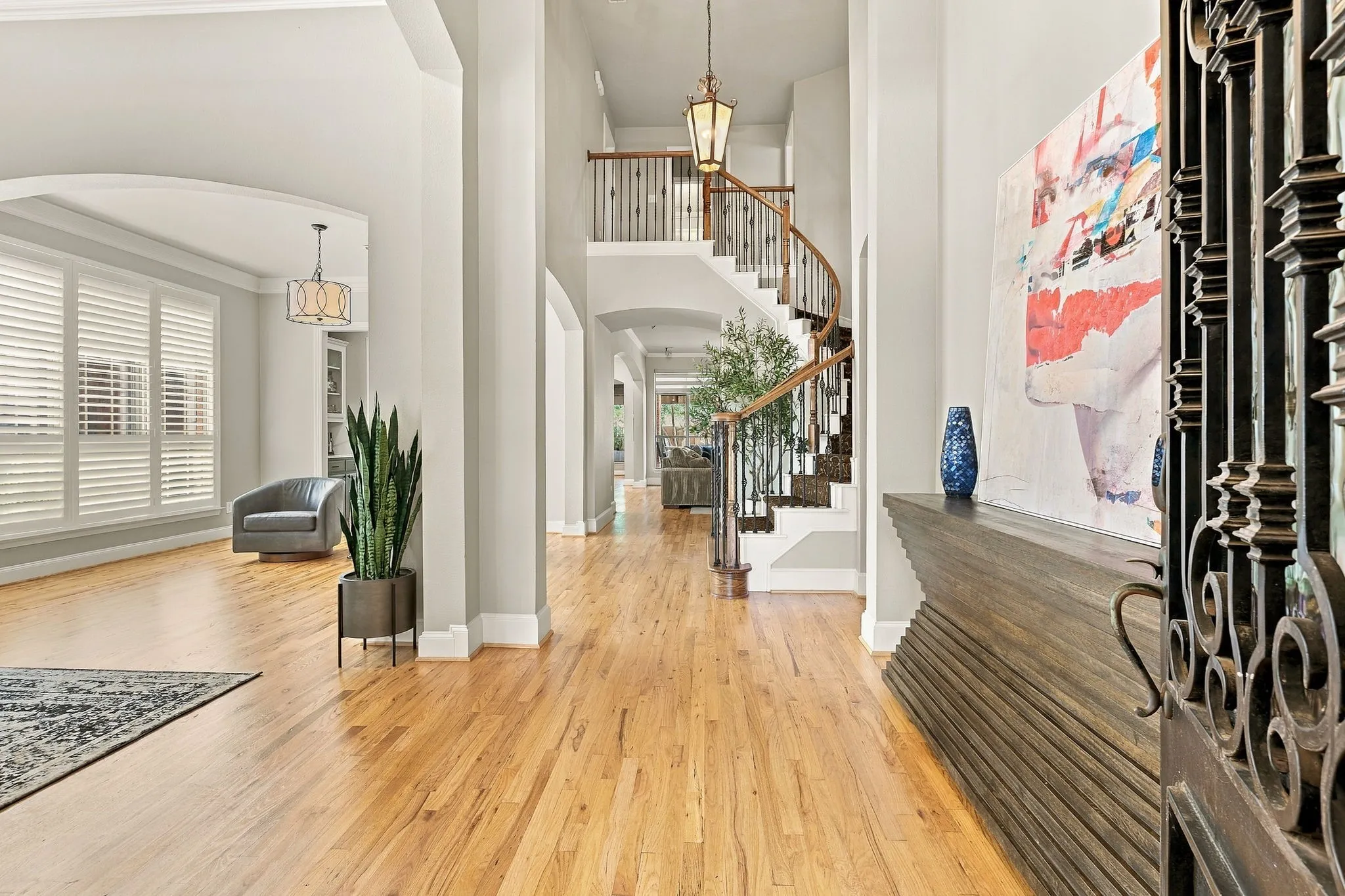 Entrance Foyer and Hallway | Wood floors continue through the entry, with arched openings connecting the front living spaces to the rest of the home.