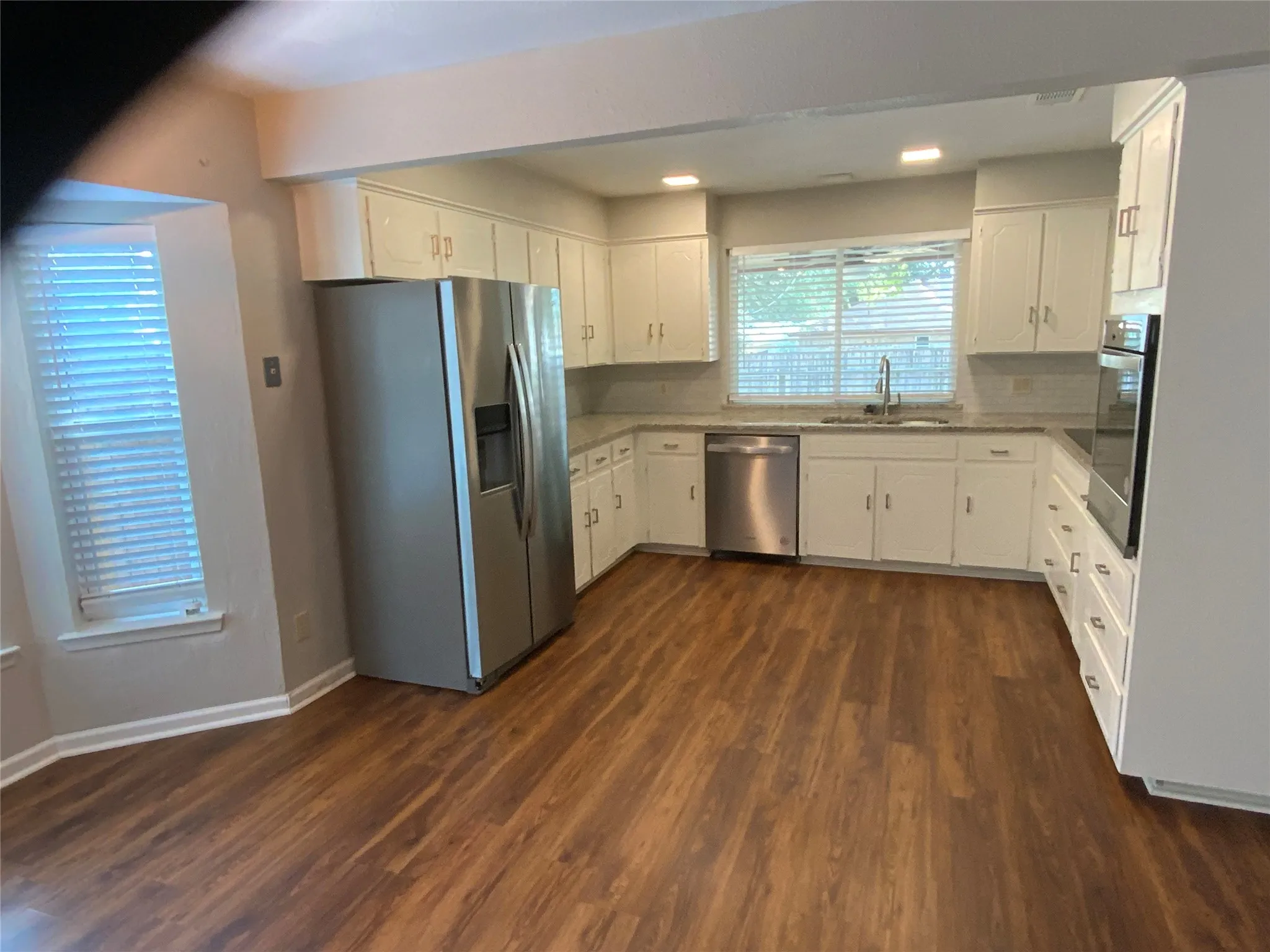 Kitchen featuring wood-finish flooring, white cabinetry, stainless steel appliances, and a built-in oven
