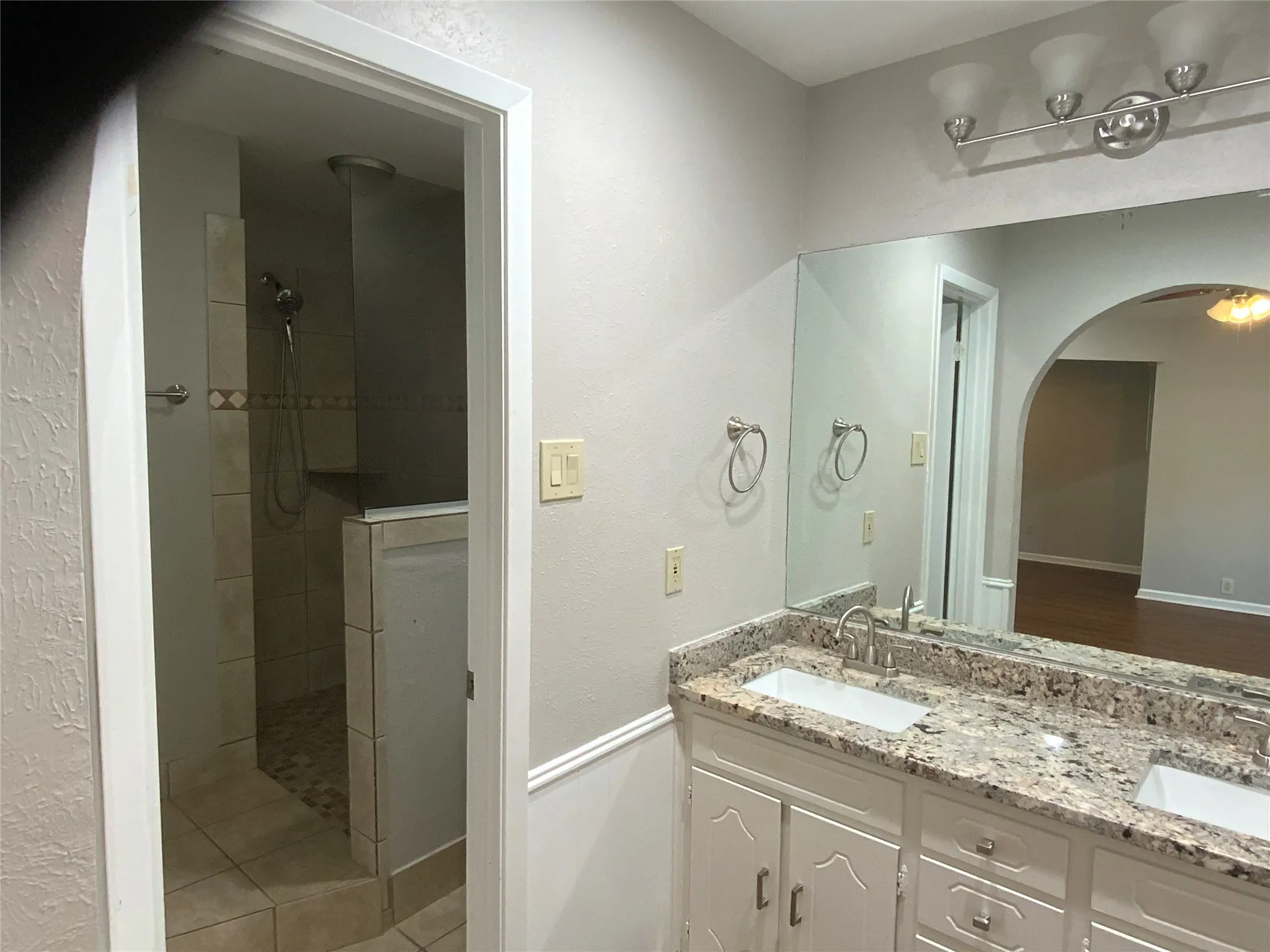 Dual vanity with granite countertop, white cabinetry, and brushed nickel fixtures