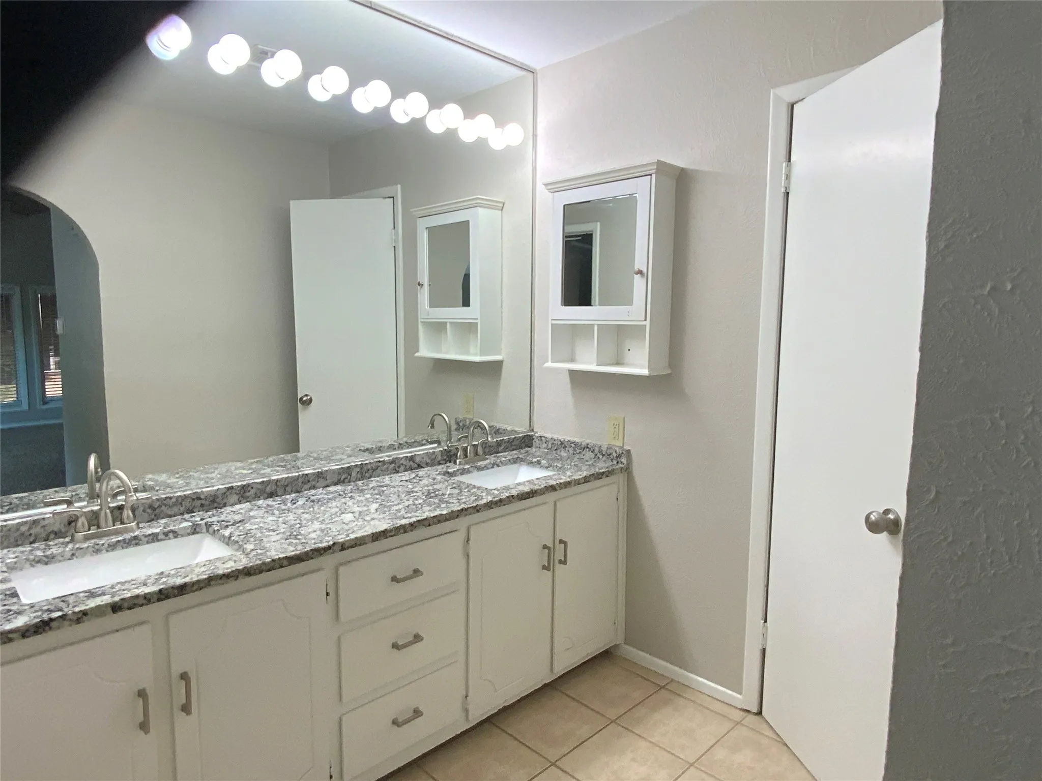 Dual vanity with gray-patterned countertops, two integrated sinks, and brushed nickel faucets