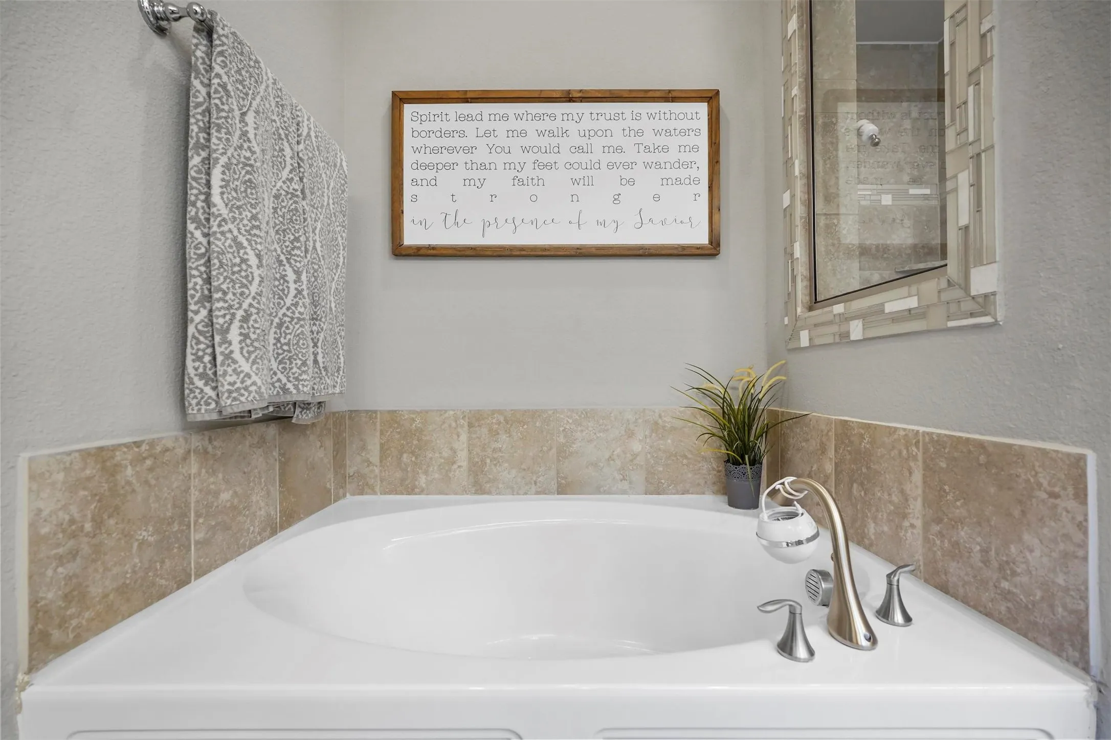 Corner soaking tub with deck-mounted faucet fixtures and stone-finish tile surround