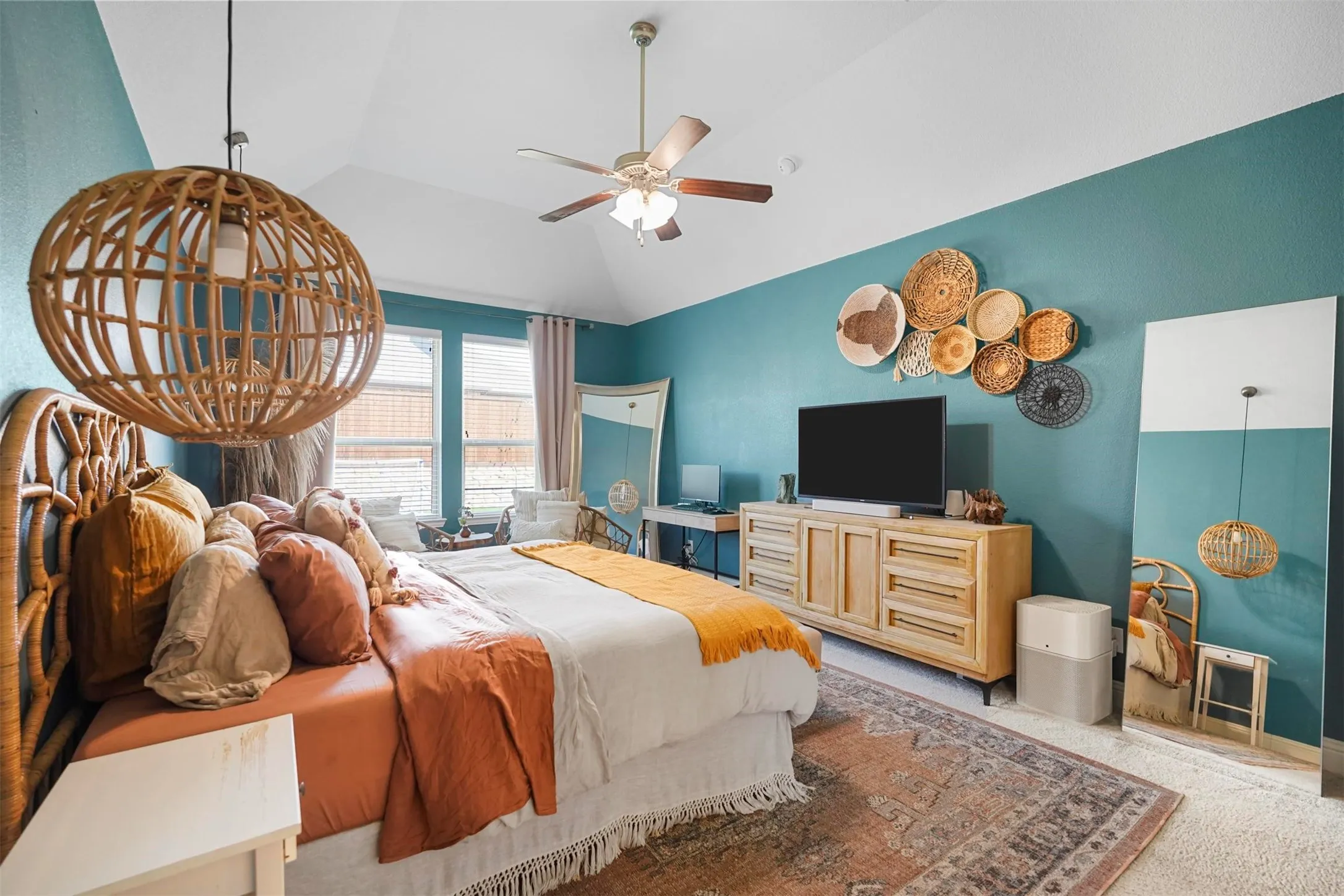 Vaulted ceiling with a ceiling fan, dual windows, and wood-finish flooring