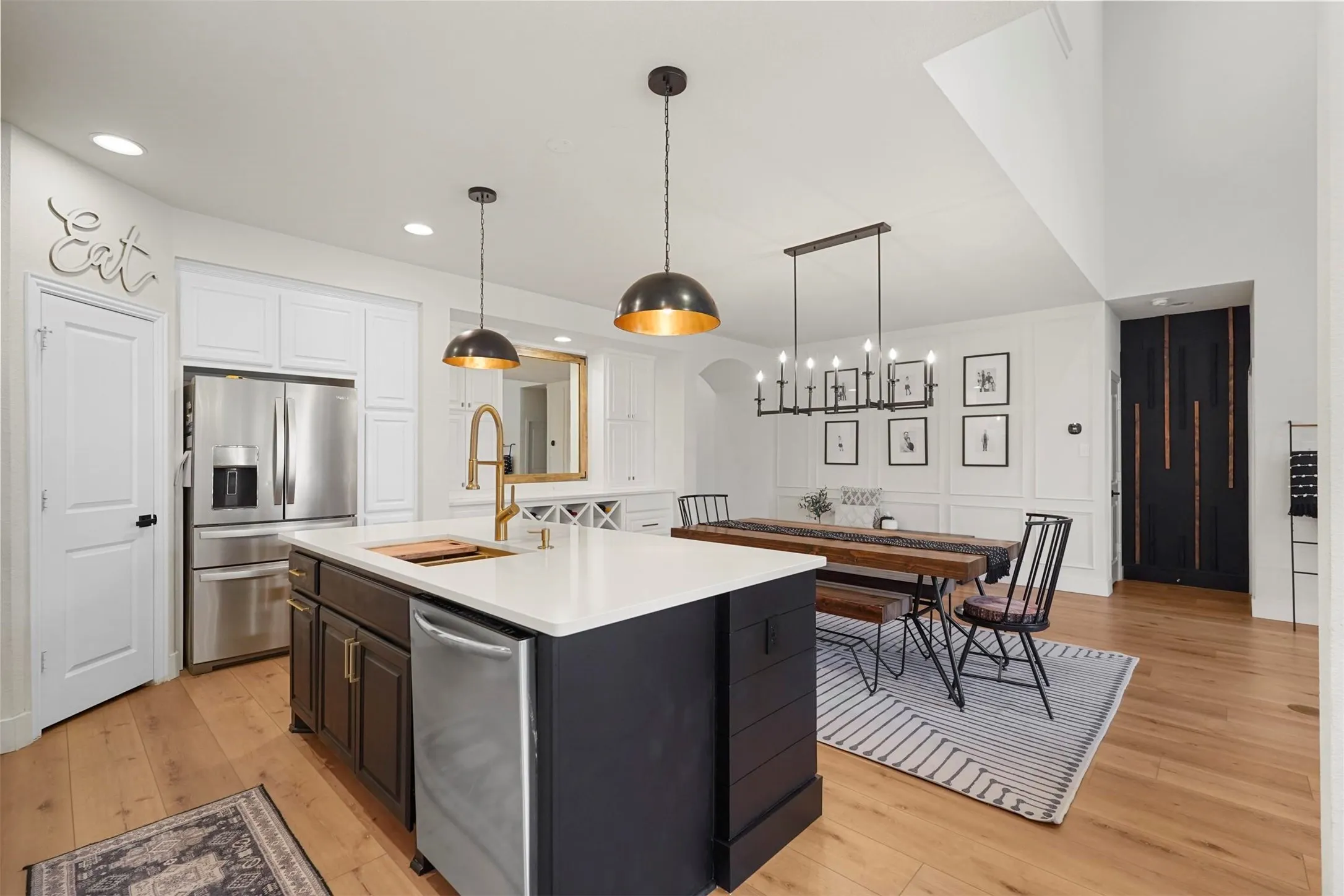 Open-concept kitchen and dining area featuring a kitchen island with a white countertop, gold-tone faucet, and pendant lighting