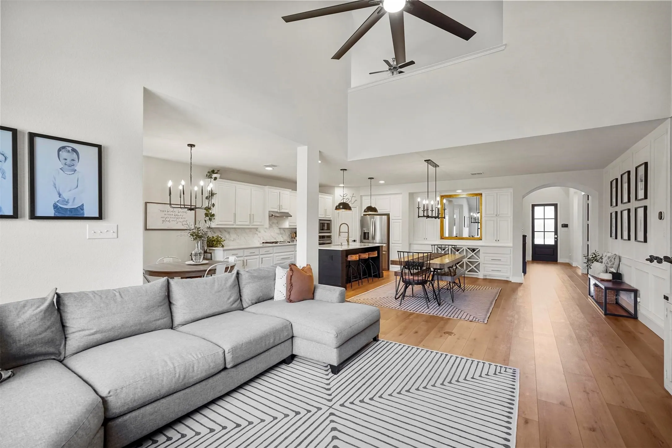 High ceilings, wood-finish flooring, white paneled accent wall, arched doorway, and built-in cabinetry