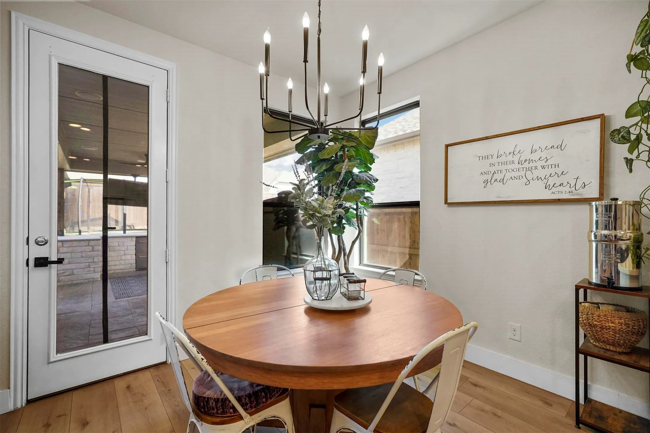 Wood-finish flooring, a full-lite glass panel door with matte black hardware, a rectangular window, and a chandelier with candelabra bulbs