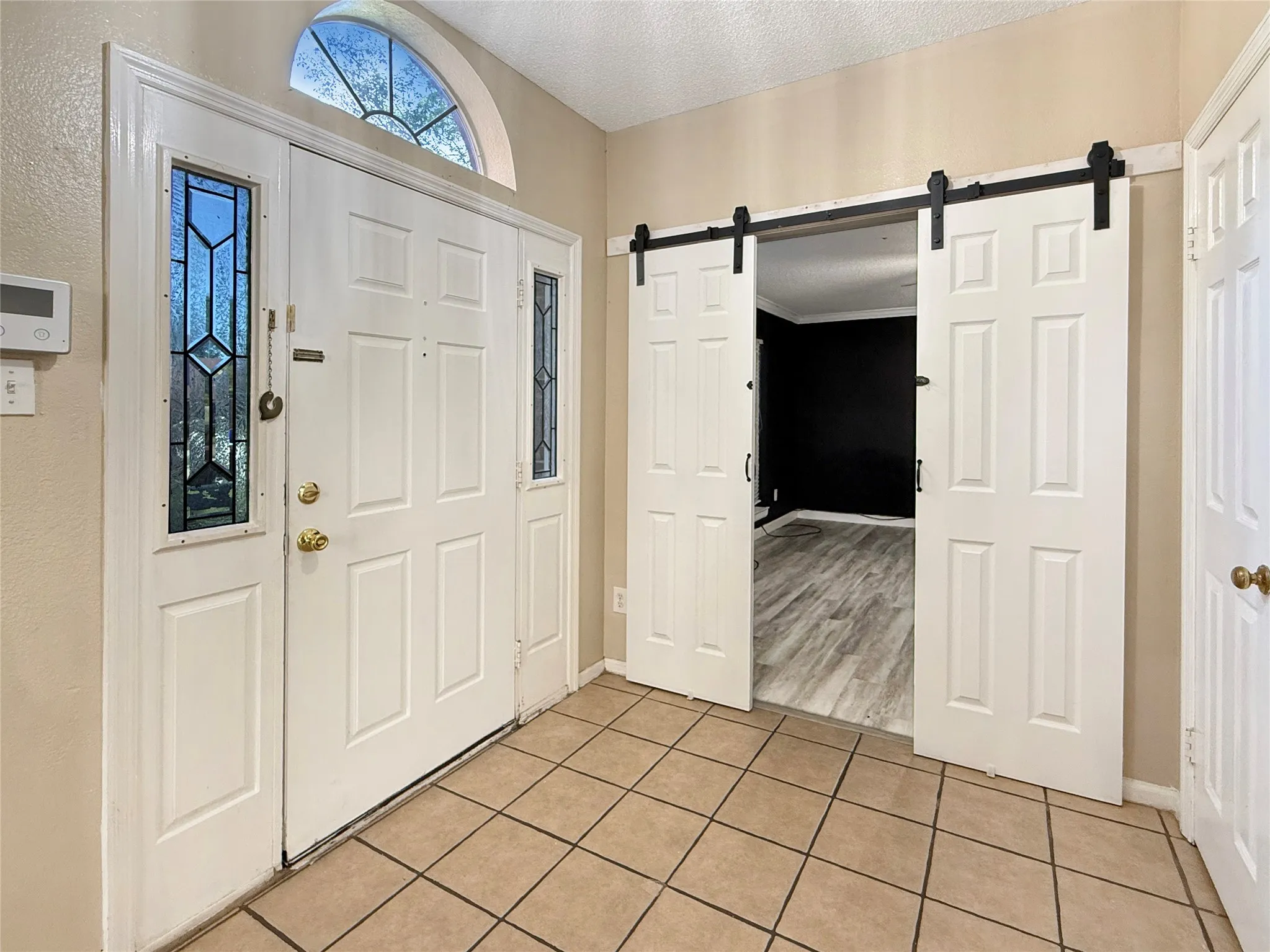 Entryway with tile flooring, a multi-panel front door with leaded glass sidelights, and a transom window