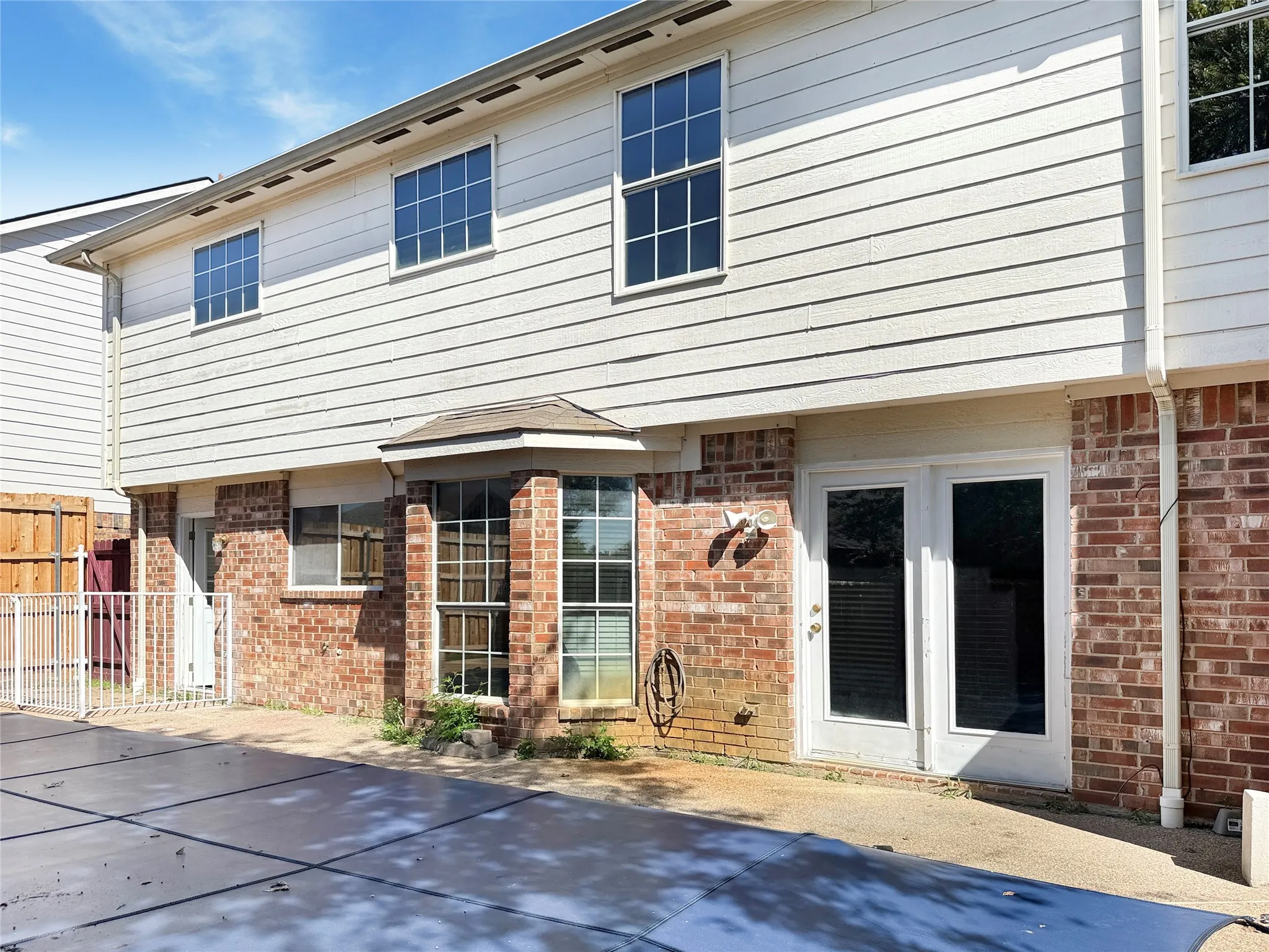 Exterior featuring brick and horizontal siding, multiple windows with grilles, and a bay​​‌​​​​‌​​‌‌​‌‌​​​‌‌​‌​‌​‌​​​‌​​ window