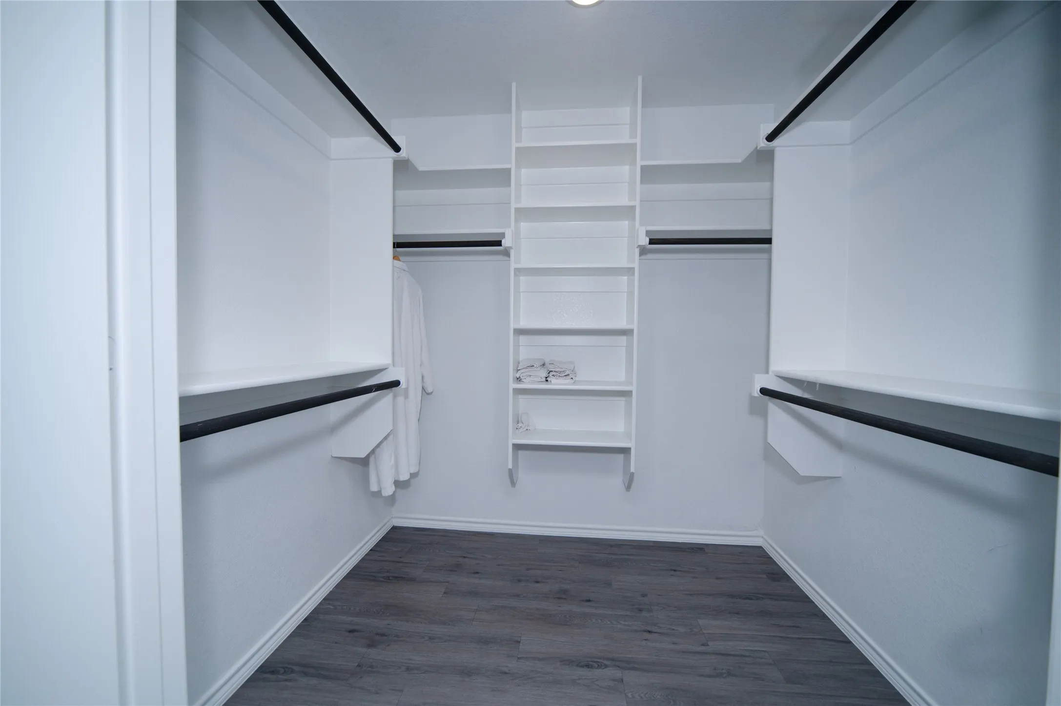Walk-in closet featuring built-in shelving, hanging rods, and wood-finish flooring