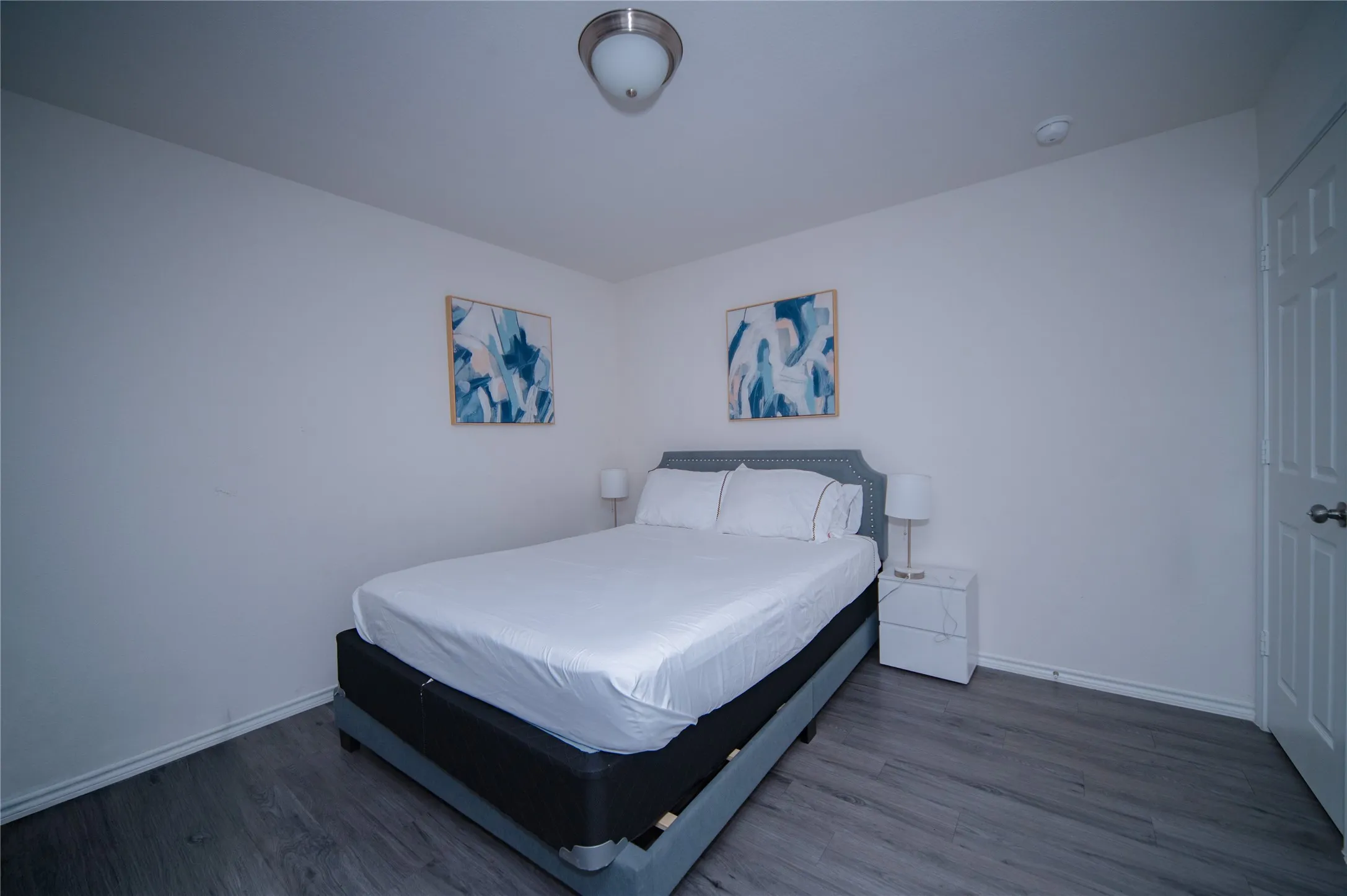 Wood-finish flooring with neutral wall paint and a flush-mount ceiling light