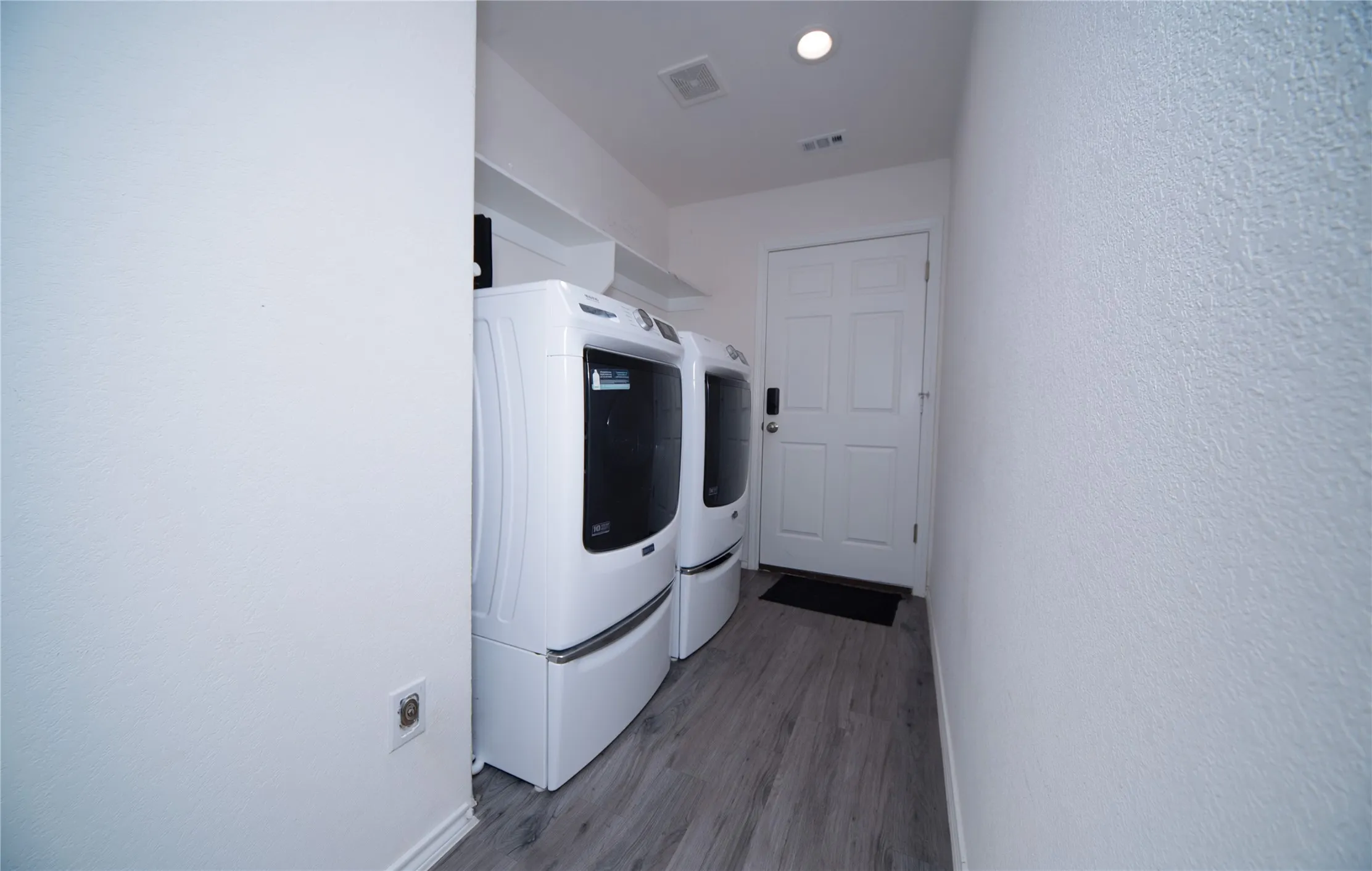 Laundry area with wood-finish flooring, white walls, built-in shelving, and recessed lighting