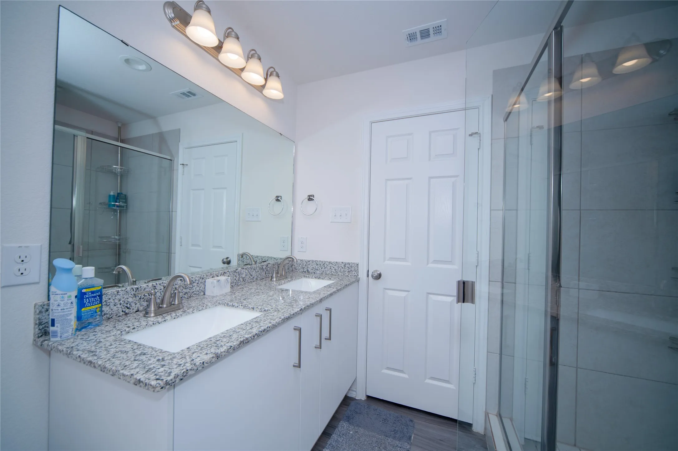 Dual vanity with granite-style countertop, undermount sinks, and brushed nickel faucets
