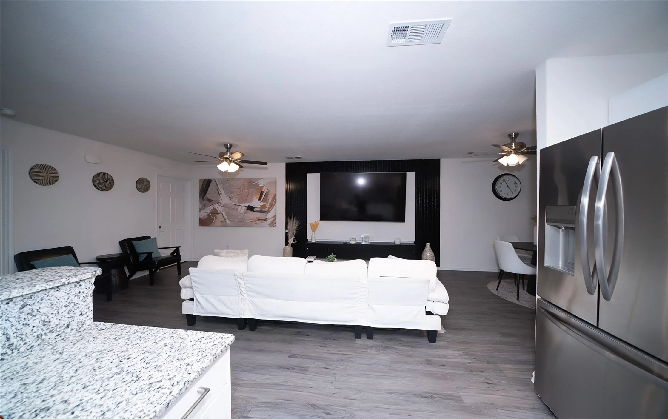 Wood-finish flooring, recessed lighting, and ceiling fans complement the living space