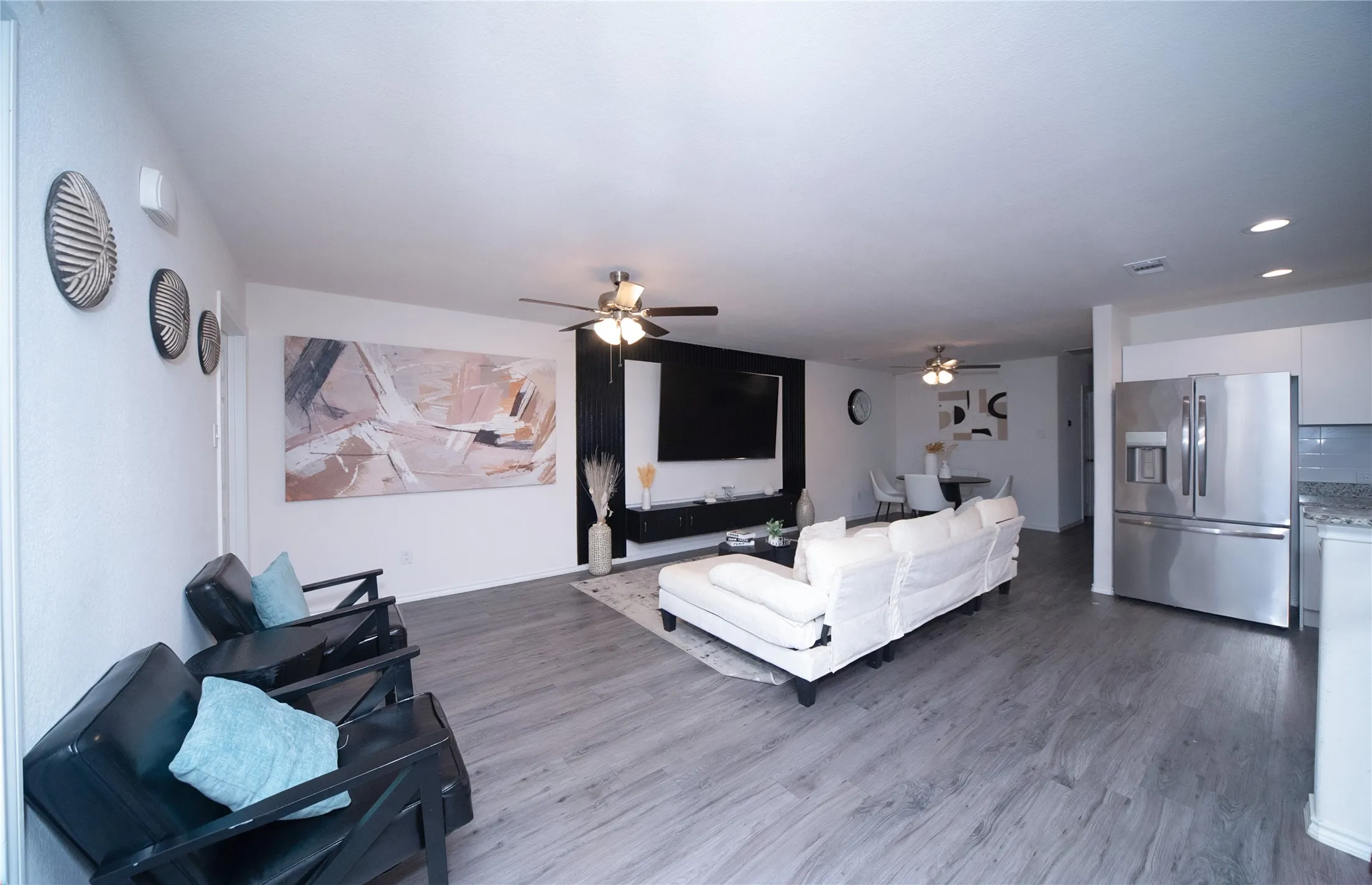 Spacious open-concept living area featuring wood-finish flooring, recessed lighting, and a ceiling fan